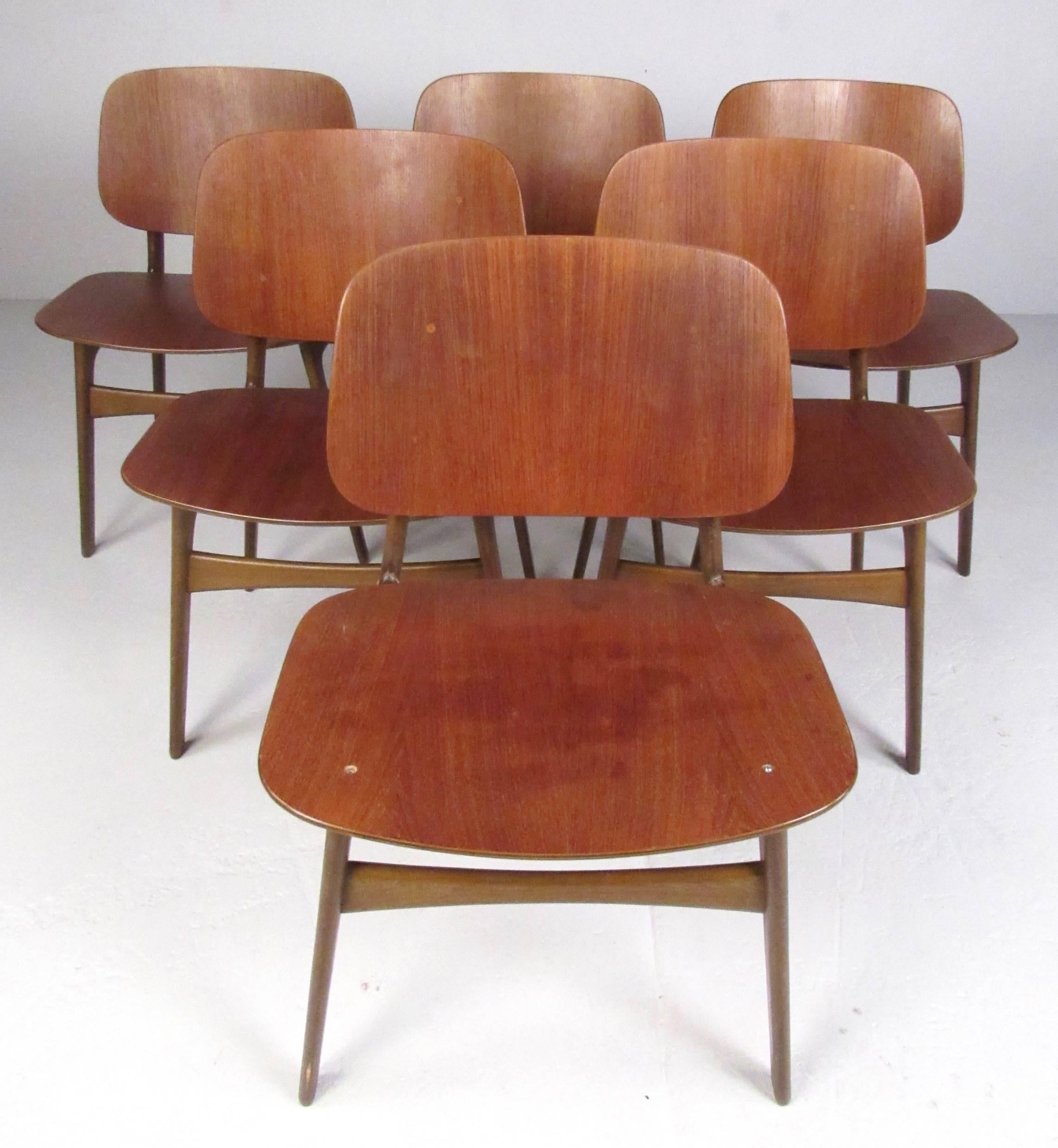 This beautiful set of six dining chairs feature Danish modern design, comfortable sculpted seats, and Mid-Century frames. The stylish mix of teak and walnut make this unique set of chairs an impressive addition to any dining room. Please confirm