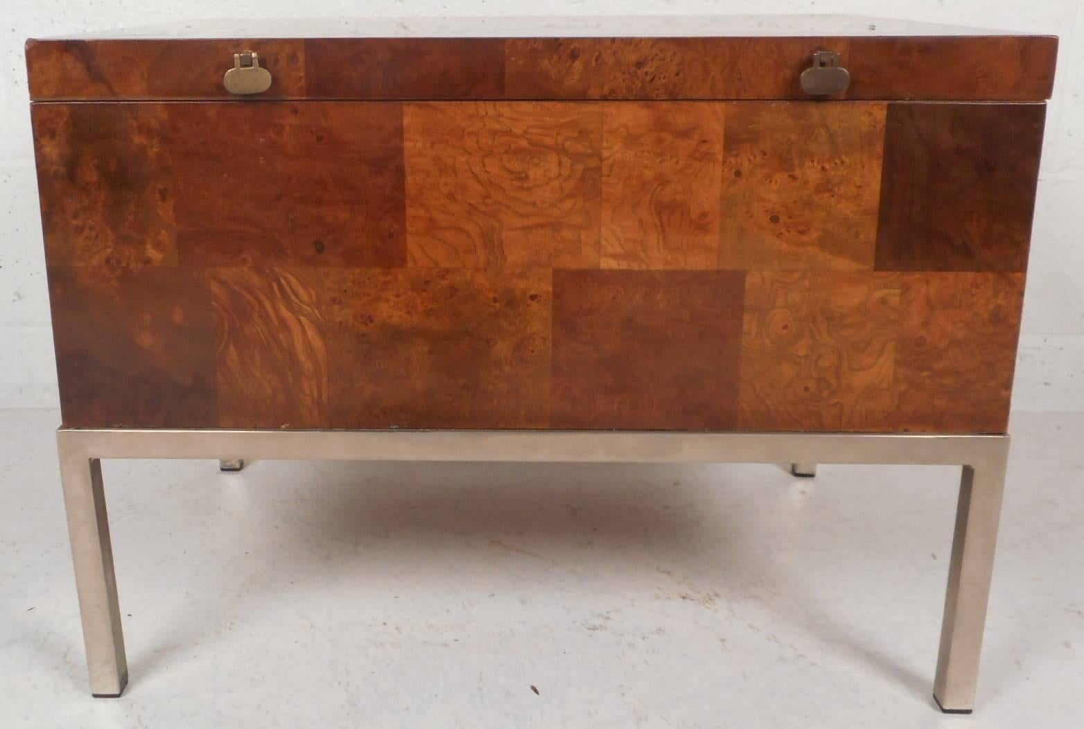 This beautiful vintage modern chest features a flip-top with unusual brass pulls that opens up to a large compartment. Elegant burl wood grain with a checkered design adds to the allure. This unique Mid-Century piece sits on top of four sturdy