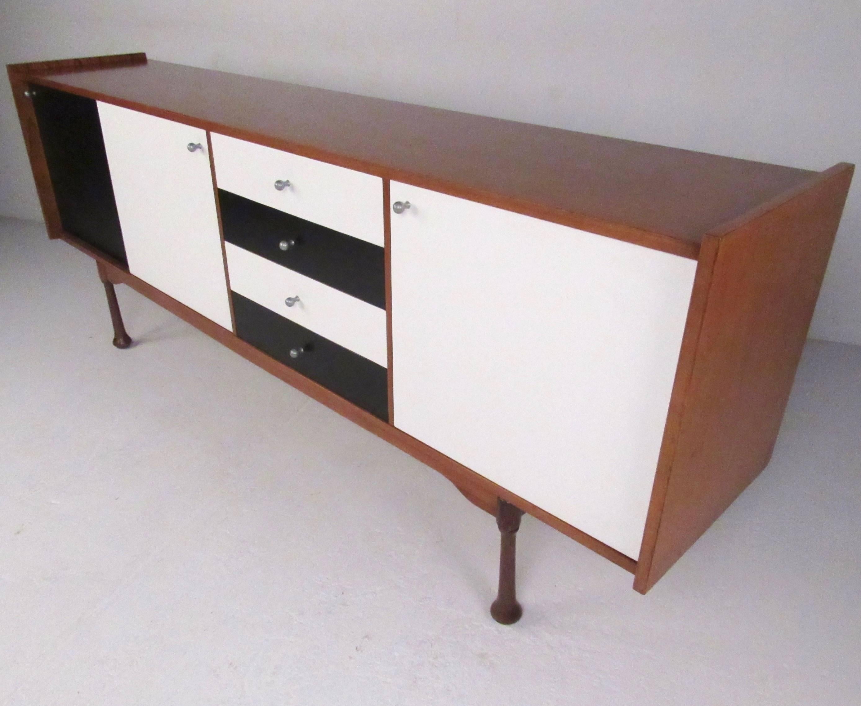 This stylish vintage sideboard features two-tone black and white cabinet fronts, raised edges, and stylish sculpted legs. This long Mid-Century server is the perfect mix of Italian modern design and spacious storage. Manufactured 1964, Milan IT.