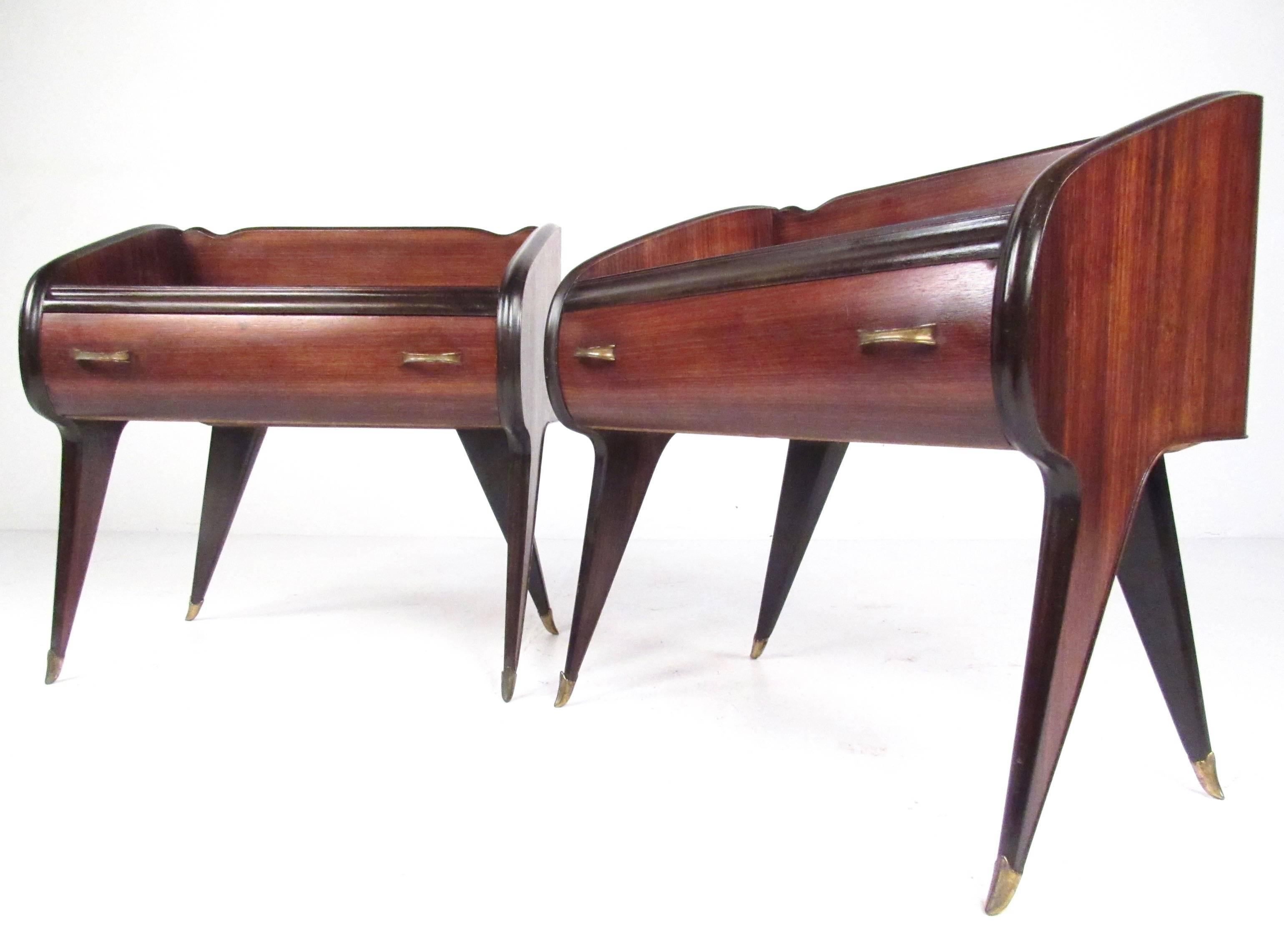 This exquisite pair of Italian modern end tables feature stylish sculpted teak design, brass details, and a dovetailed drawer for extra storage. Unique Mid-Century design makes these an impressive addition to any setting. Please confirm item