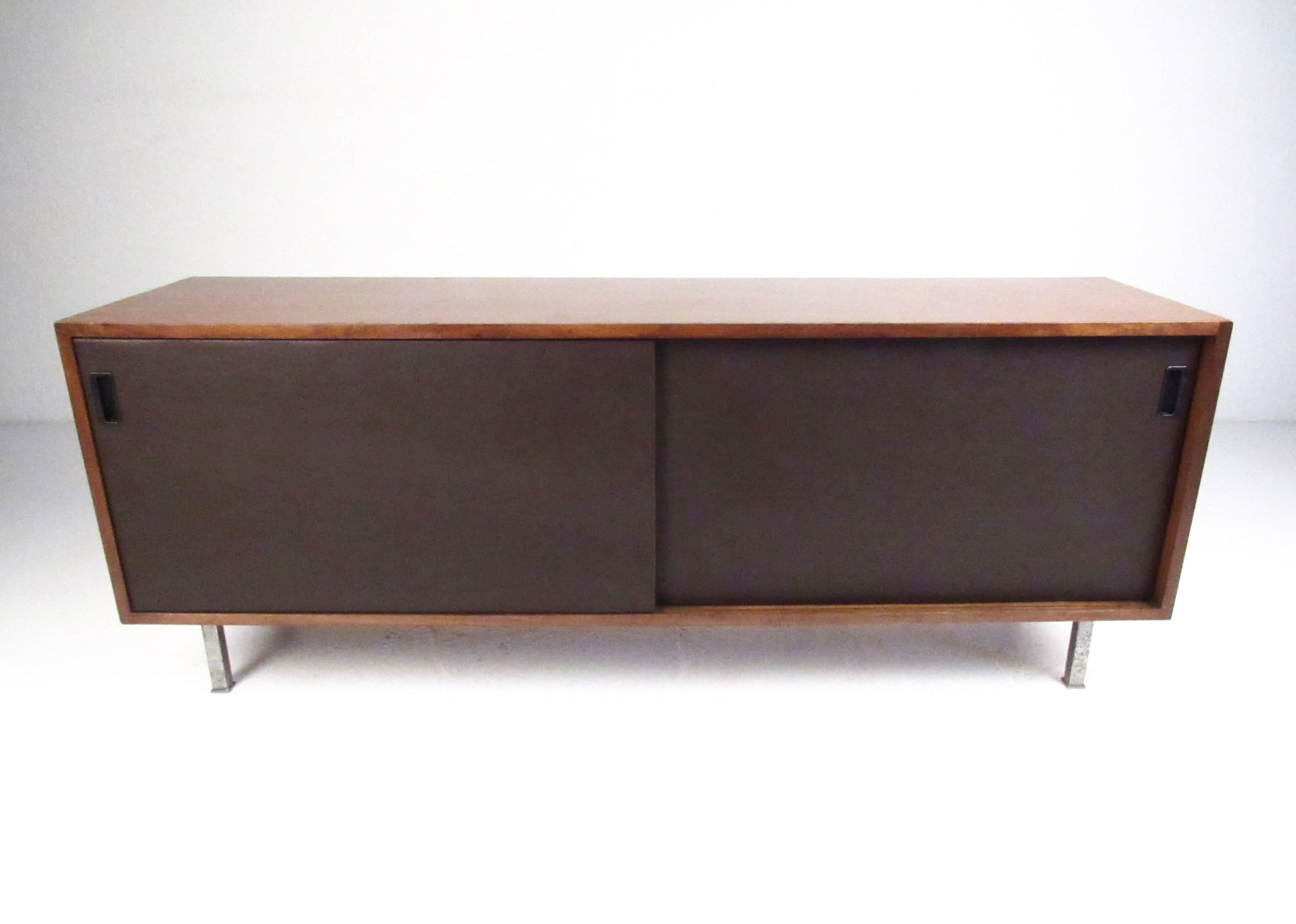 This unique Mid-Century cabinet features spacious sliding door storage and sleek modern design. Iconic design by Florence Knoll, this spacious console cabinet is ideal for use as a television stand, office storage, or for dining room use. Steel