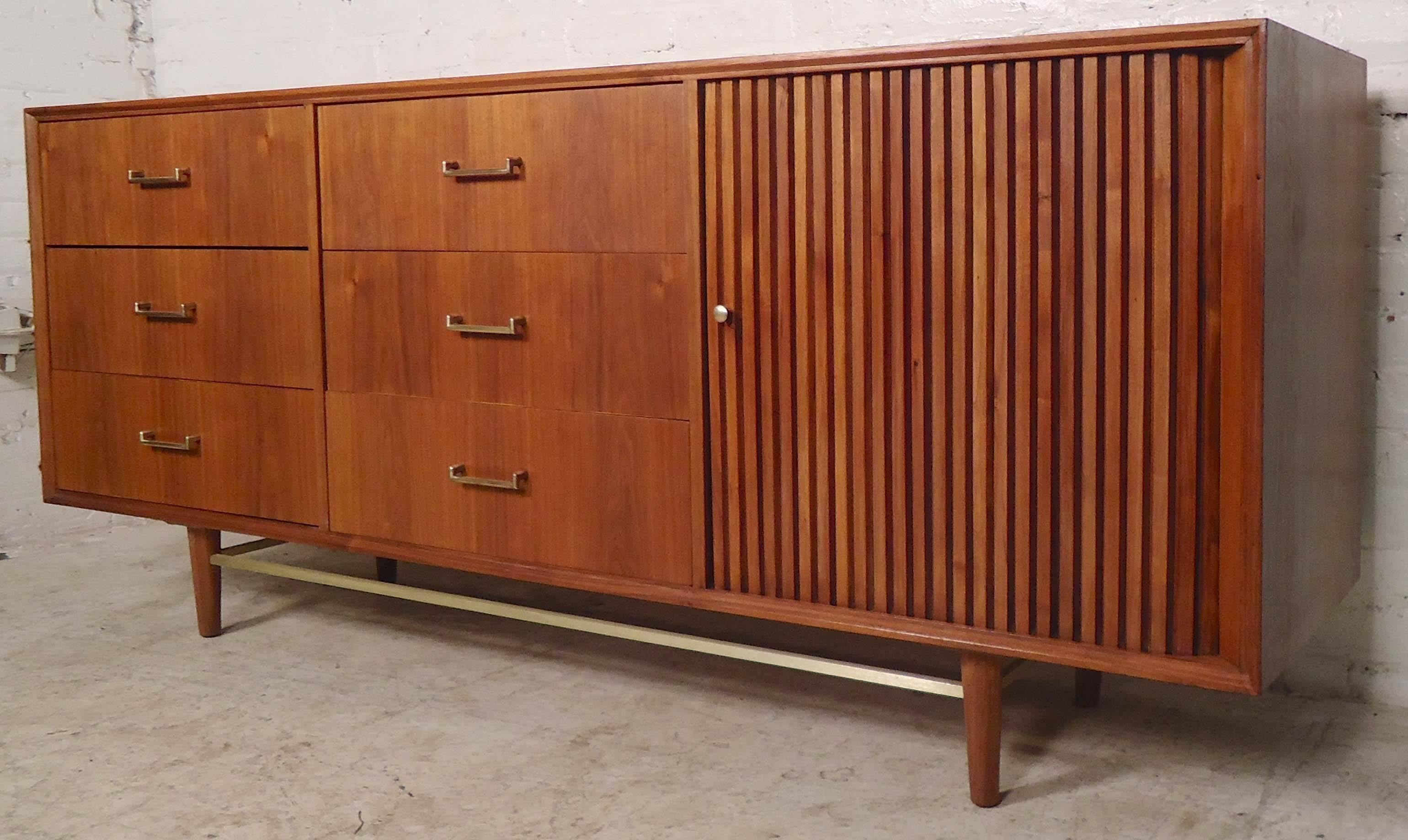 Long vintage dresser with nine total drawers in walnut grain. Sleek straight lines, brass hardware and unique tambour door. Gives a great modern look to the bedroom.

(Please confirm item location - NY or NJ - with dealer).
 