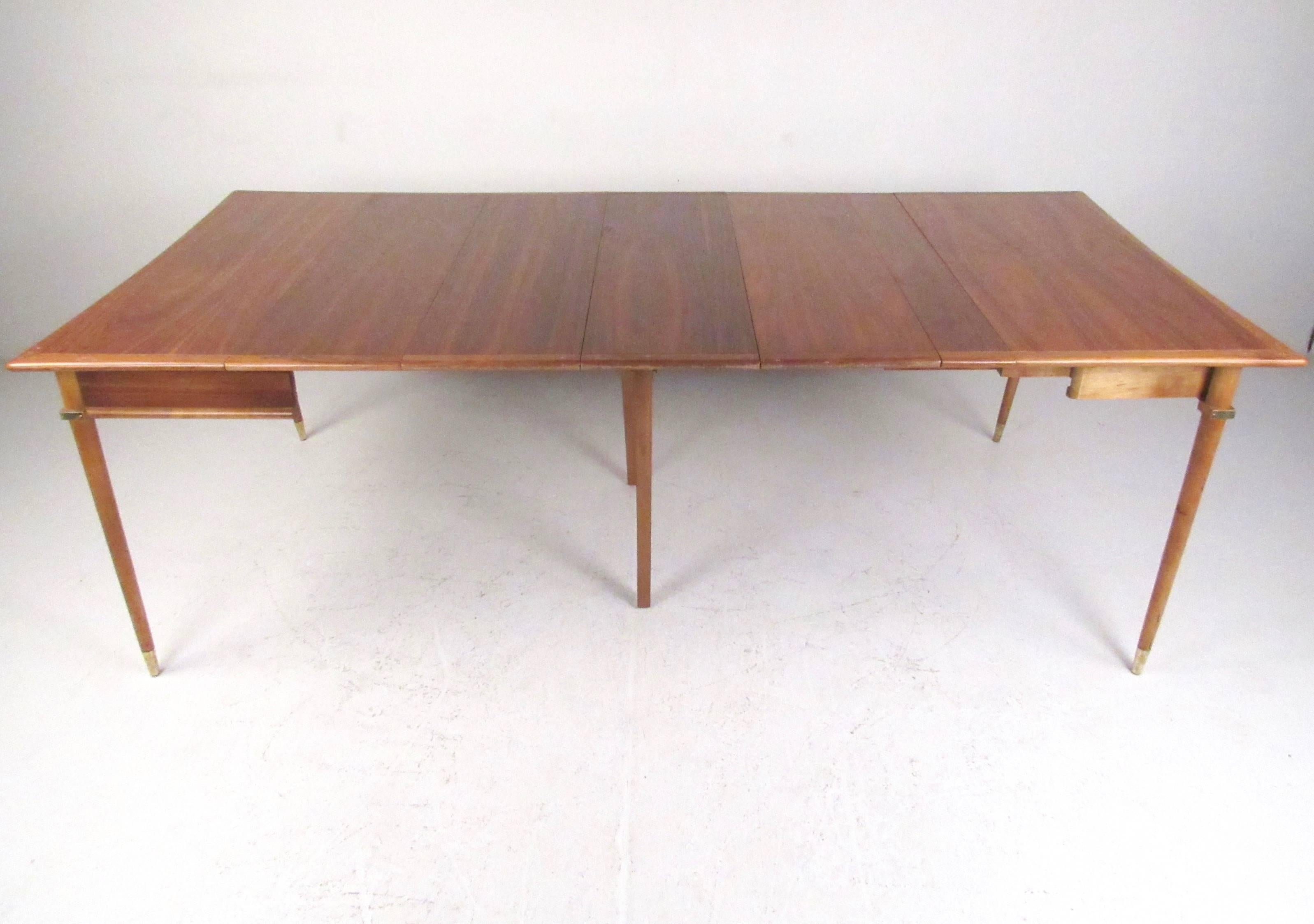 This unique and innovative console table expands from 20 inches up to 88 inches with built in pull-out leaves and four additional drop in leaves. Tapered legs, two-tone finish, and brass sabot feet add to the Mid-Century Modern appeal of this