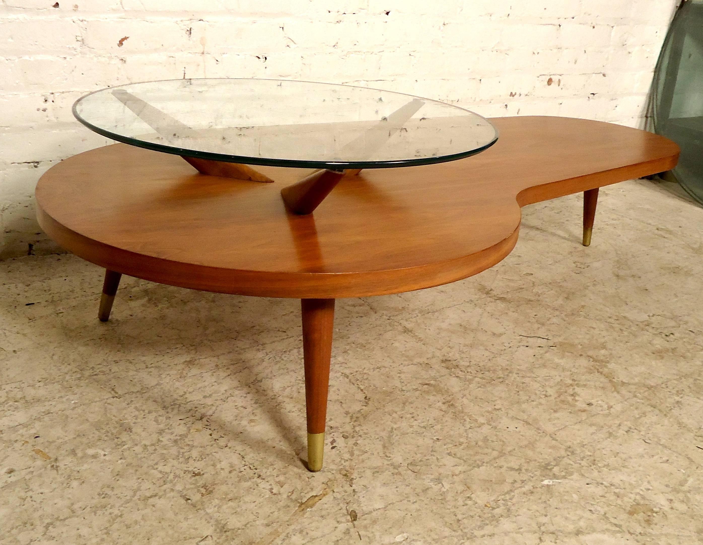 This very unique Mid-Century Modern coffee table features two-tiers, one glass top elevated above a kidney shaped bottom tier on a set of three tapered legs.

Please confirm item location (NY or NJ).