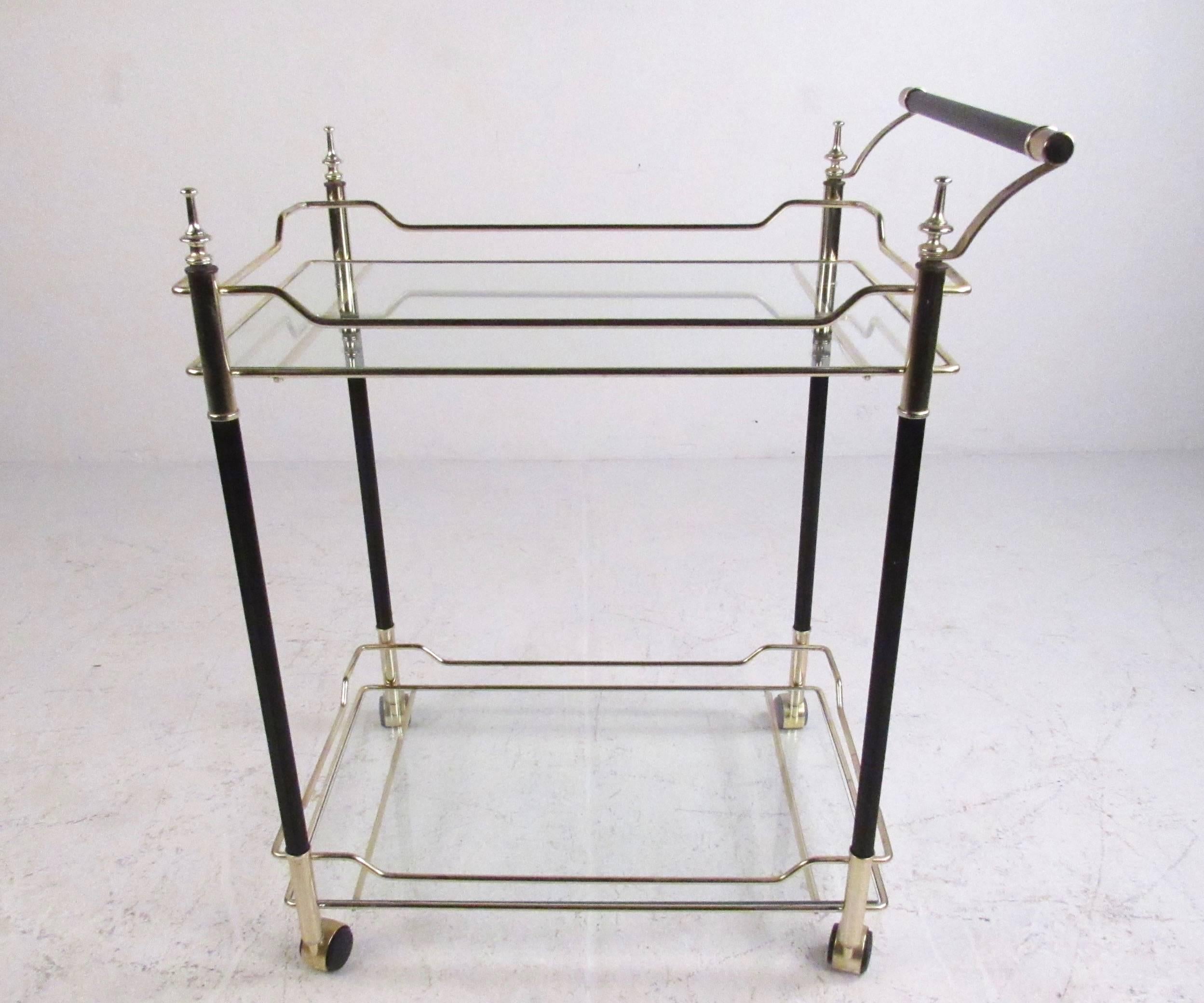 This stylish two-tier bar cart features elegant Mid-Century design and uniquely detailed trim. Wonderful mix of brass, glass and black lacquer adds to the vintage appeal of this versatile Italian serving cart. Please confirm item location (NY or NJ).