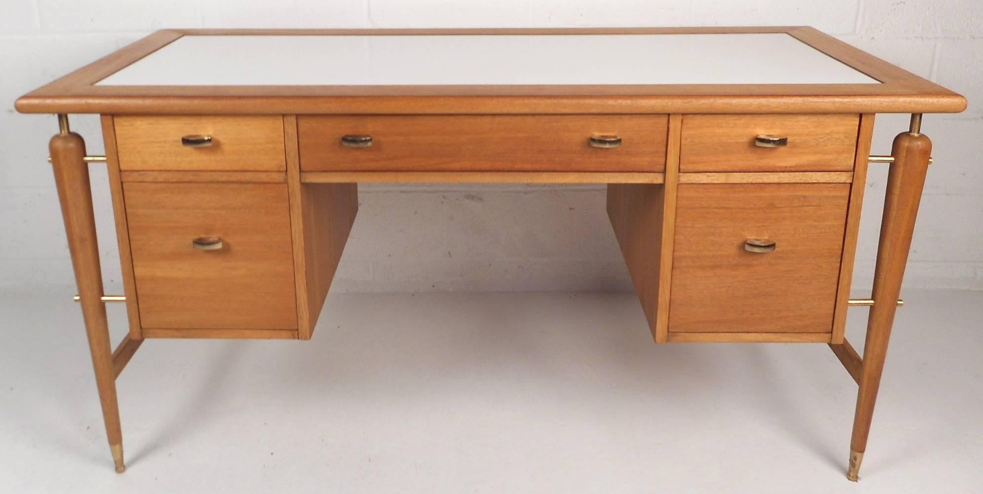 This stunning vintage modern desk is made of mahogany wood and features a unique white laminate top. This mid-century case piece offers plenty of work space and room for storage within its five large drawers. Stylish floating design with four long