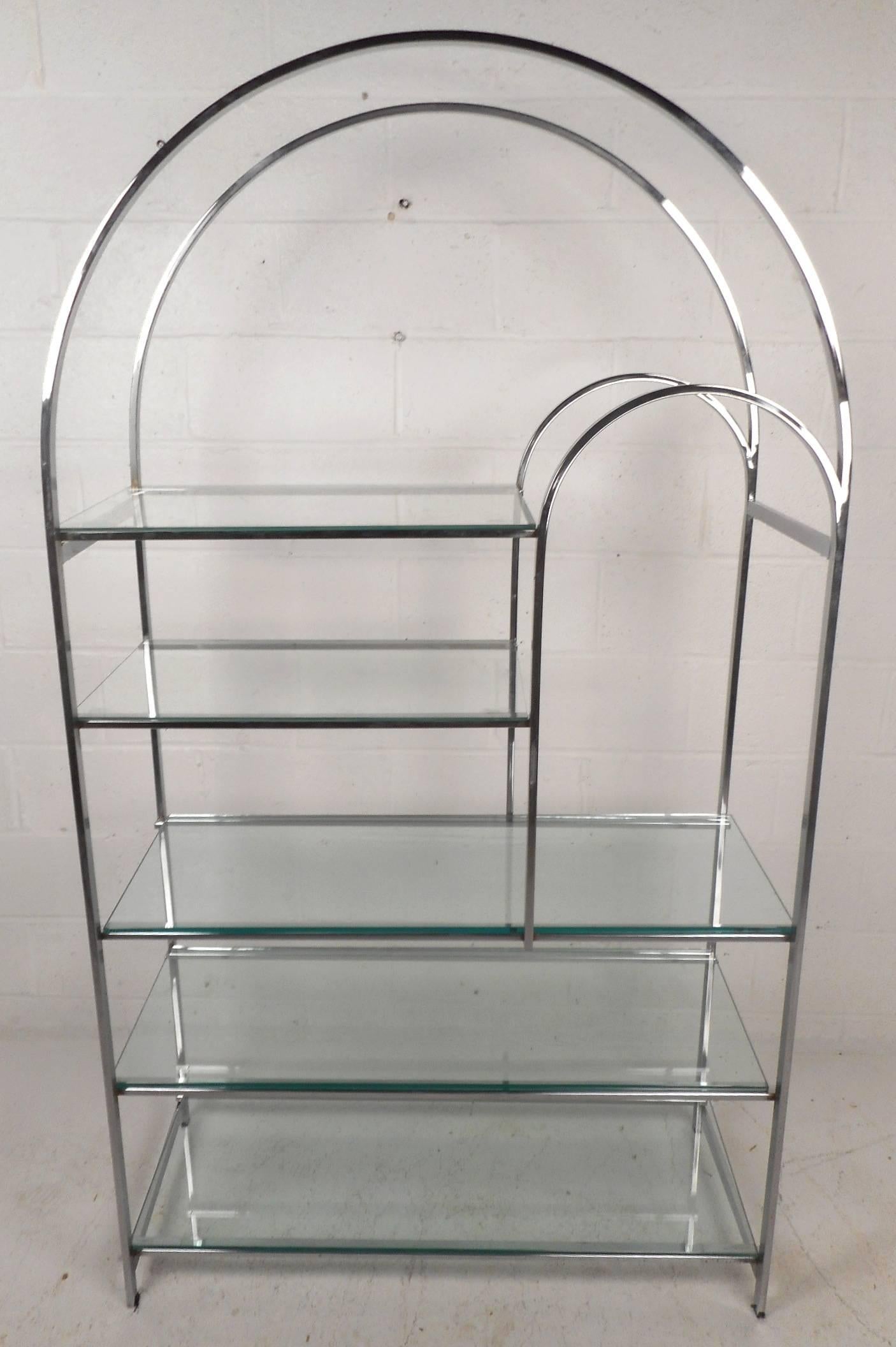 This elegant vintage modern display shelf makes an ideal storage piece for a variety of interiors with its five thick glass shelves. Sleek design is made of heavy chrome and features an arched top with a unique smaller arch on the left side allowing