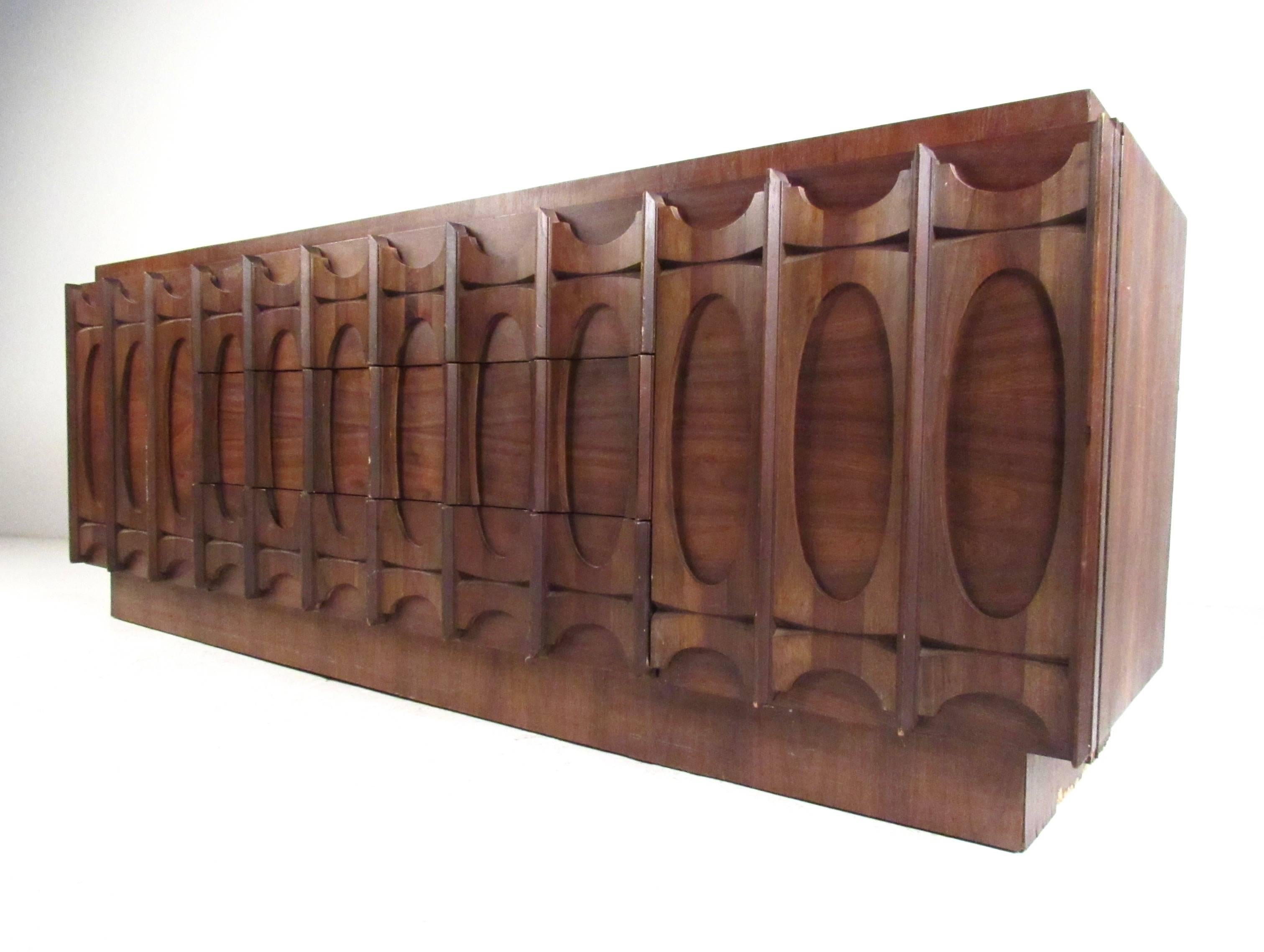 This sculptural walnut dresser features unique Brutalist design with plenty of storage for any bedroom setting. The unique cat eye Kent Coffey/Brasilia style trim on the piece is accentuated by the rich vintage finish. Please confirm item location