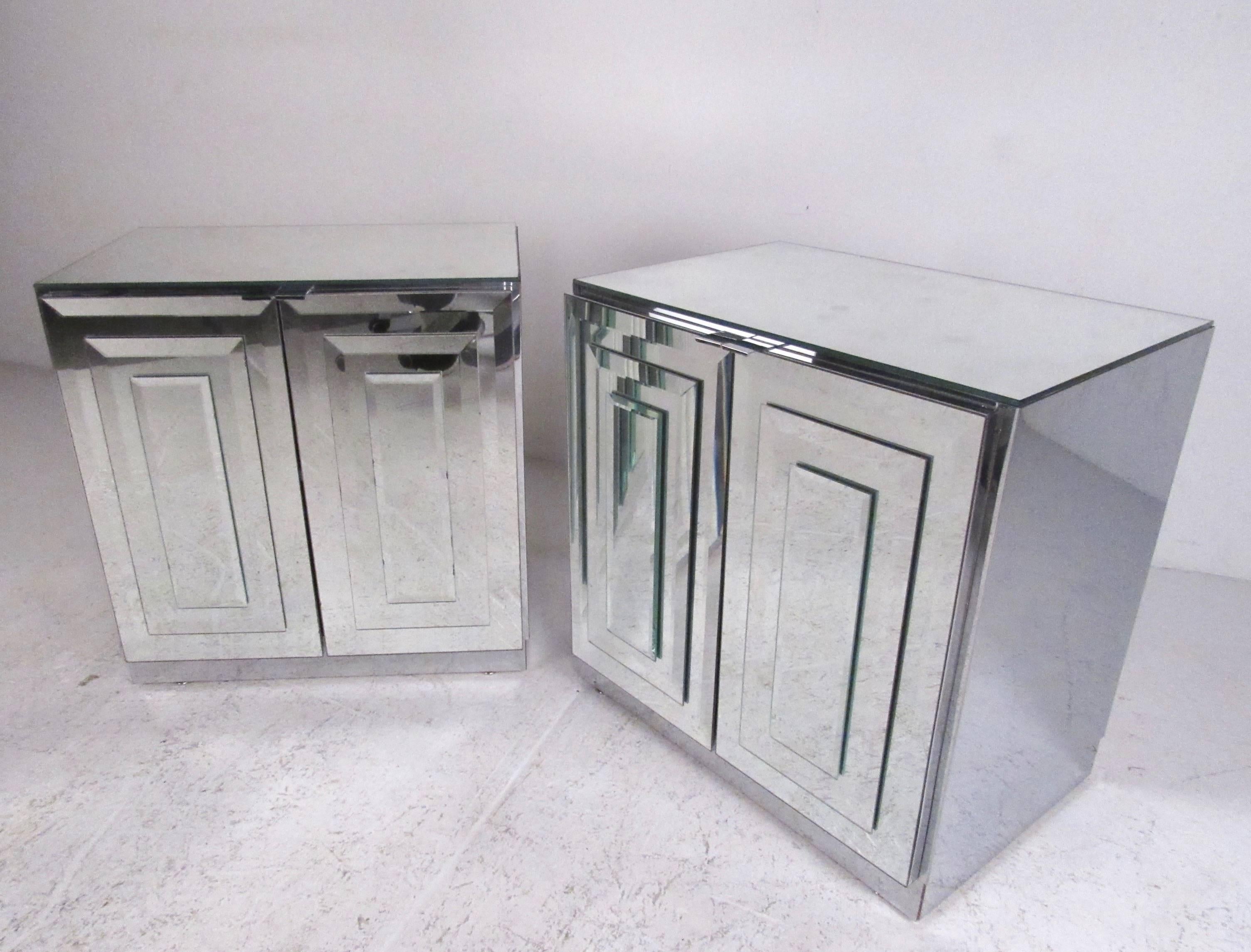 This stylish pair of Mid-Century Modern end tables by Ello Furniture features elegant mirrored finish, with sculptural glass fronts and sides. Interior cabinet space offers adjustable shelf storage ideal for bedside or living room use. Please