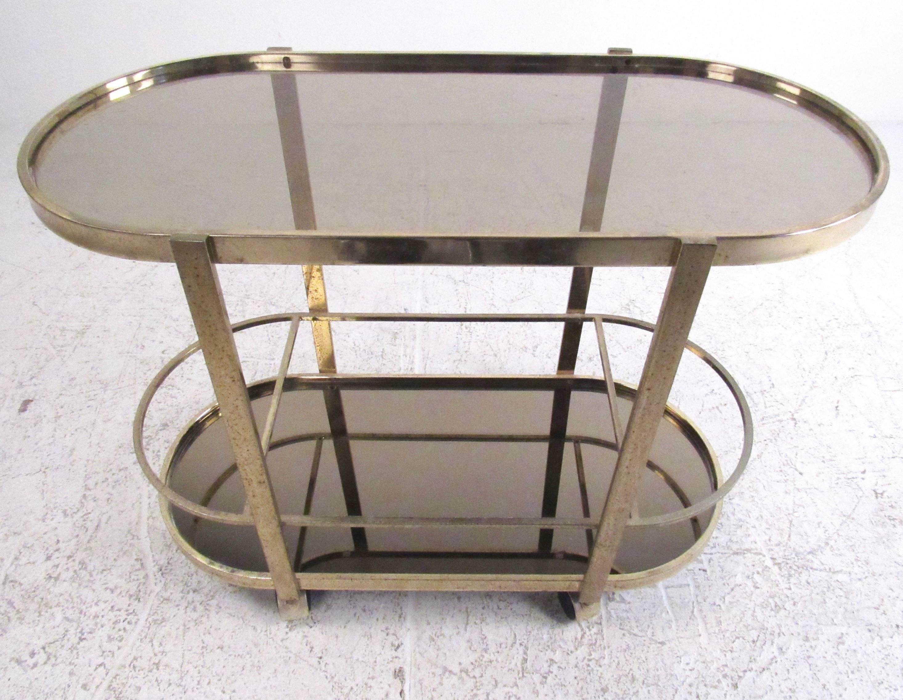 This stylish modern bar cart features oxidized brass finish with two tier oval shelves for storage and display. Mirrored glass bottom and Mid-Century style make this a versatile and attractive cart for bar service or storage. 
Please confirm item