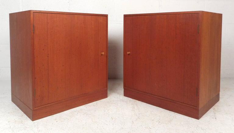 This gorgeous pair of vintage modern end tables feature a compartment for storage with a shelf hidden behind a cabinet door. Sleek and simple design with unique sculpted door pulls and a rich teak finish. This stunning Mid-Century pair of