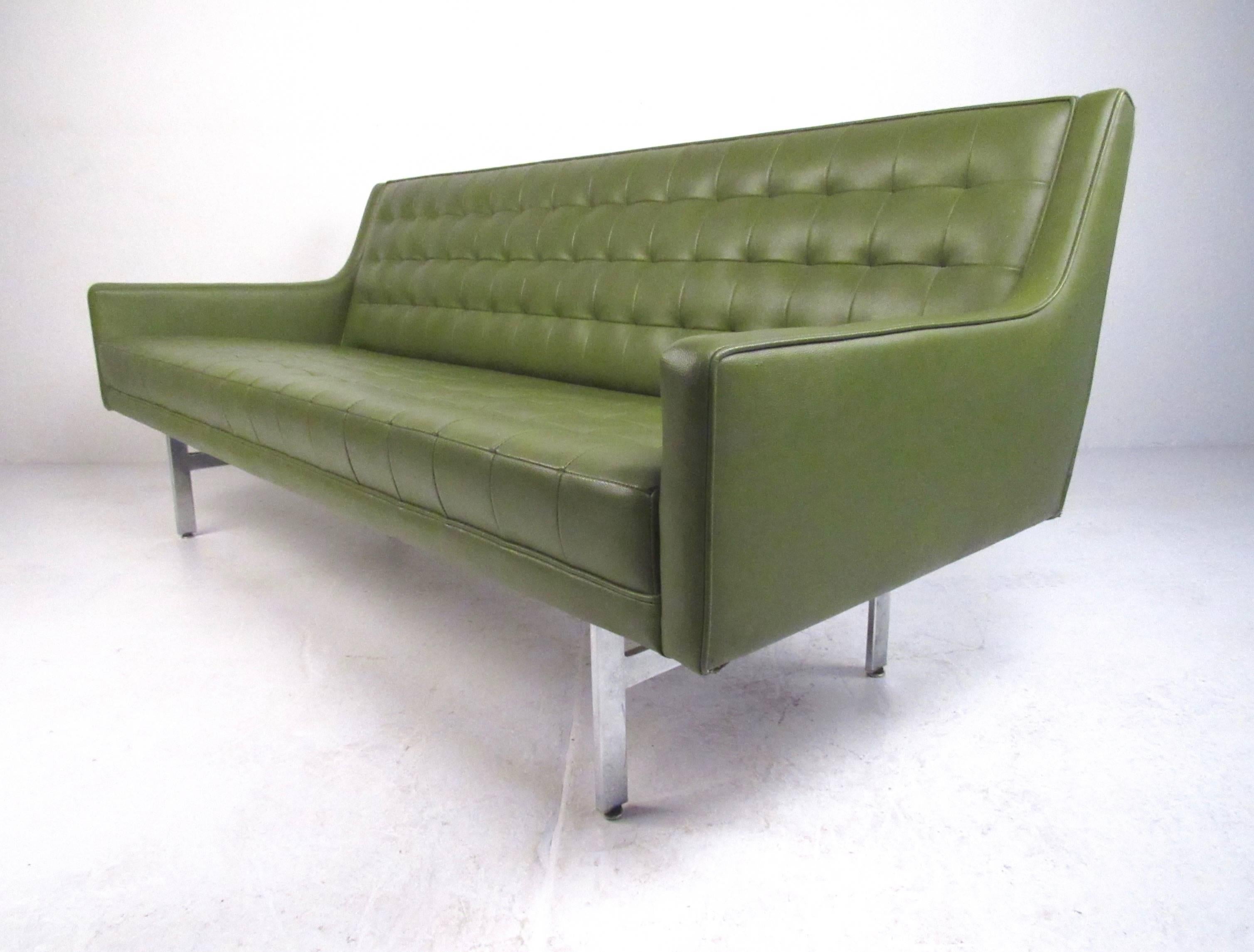 This stunning vintage sofa features eye-catching vinyl upholstery, shapely Mid-Century design, and sturdy chrome legs. Unique tufted upholstery makes this long green sofa an impressive retro modern addition to any interior. Please confirm item