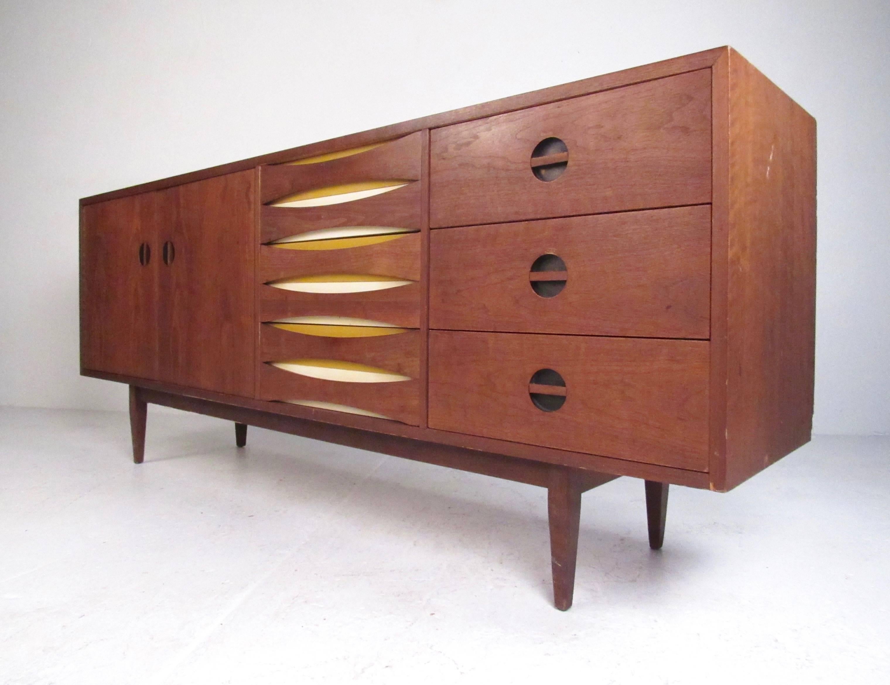 This beautiful Mid-Century Modern sideboard has a unique vintage walnut finish, stylish drawer pulls, and tapered hardwood legs. This impressive modern credenza combines side by side drawer and cabinet storage and makes for a versatile and