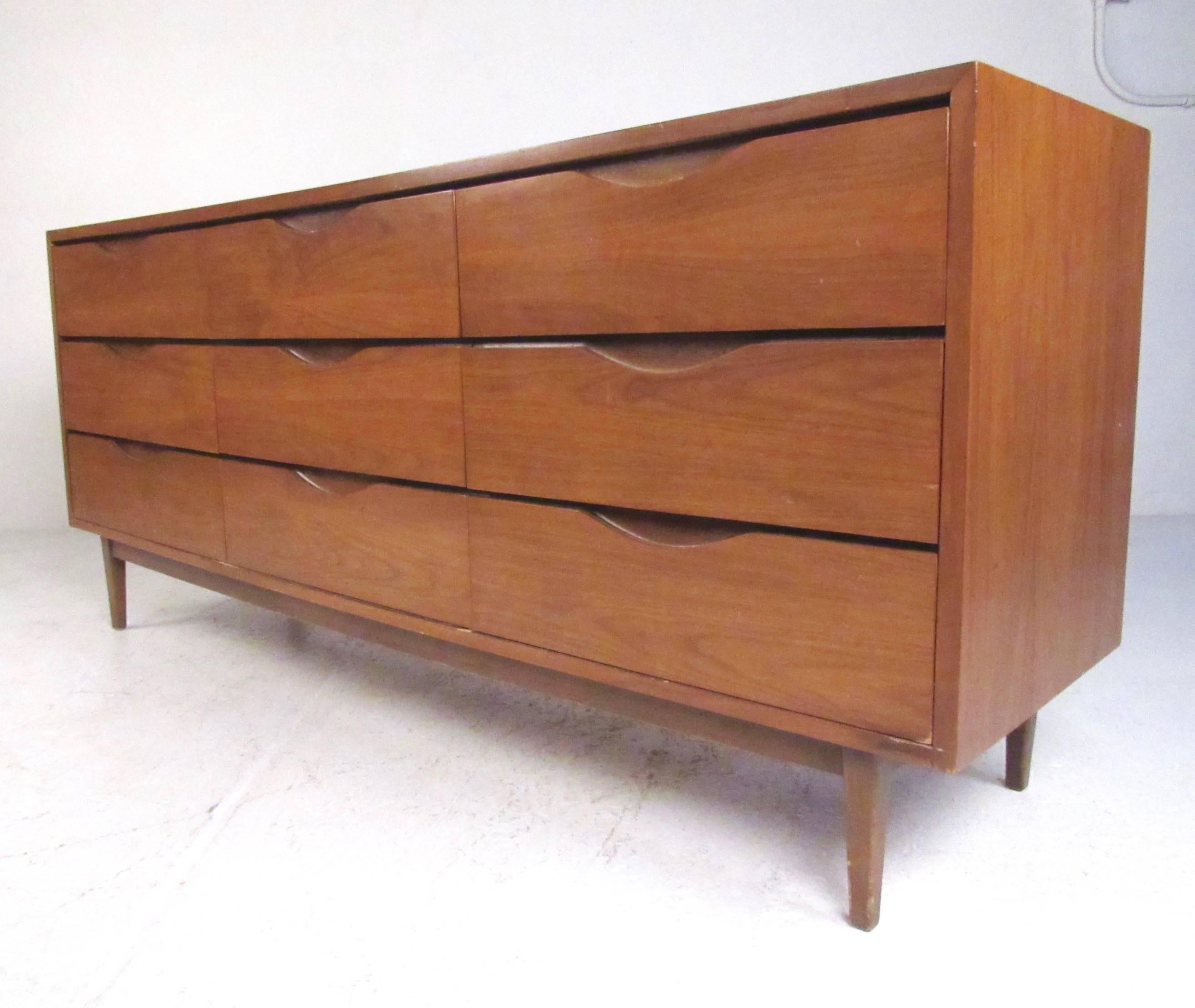 This stylish vintage walnut dresser features cut-away drawer pulls, tapered legs, and a rich natural wood finish. Plenty of storage for any setting, additional highboy dresser and matching nightstands available. Please confirm item location (NY or