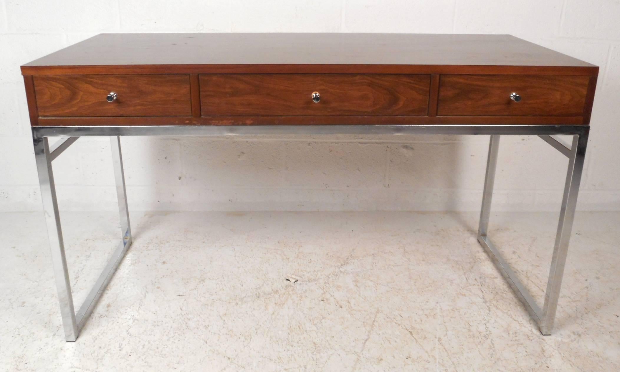 This gorgeous vintage modern desk is designed in the style of Milo Baughman. This stylish and sturdy piece sits on a heavy chrome frame with boxed sides. Unique design has three large drawers with unusual chrome pulls. This versatile desk has a