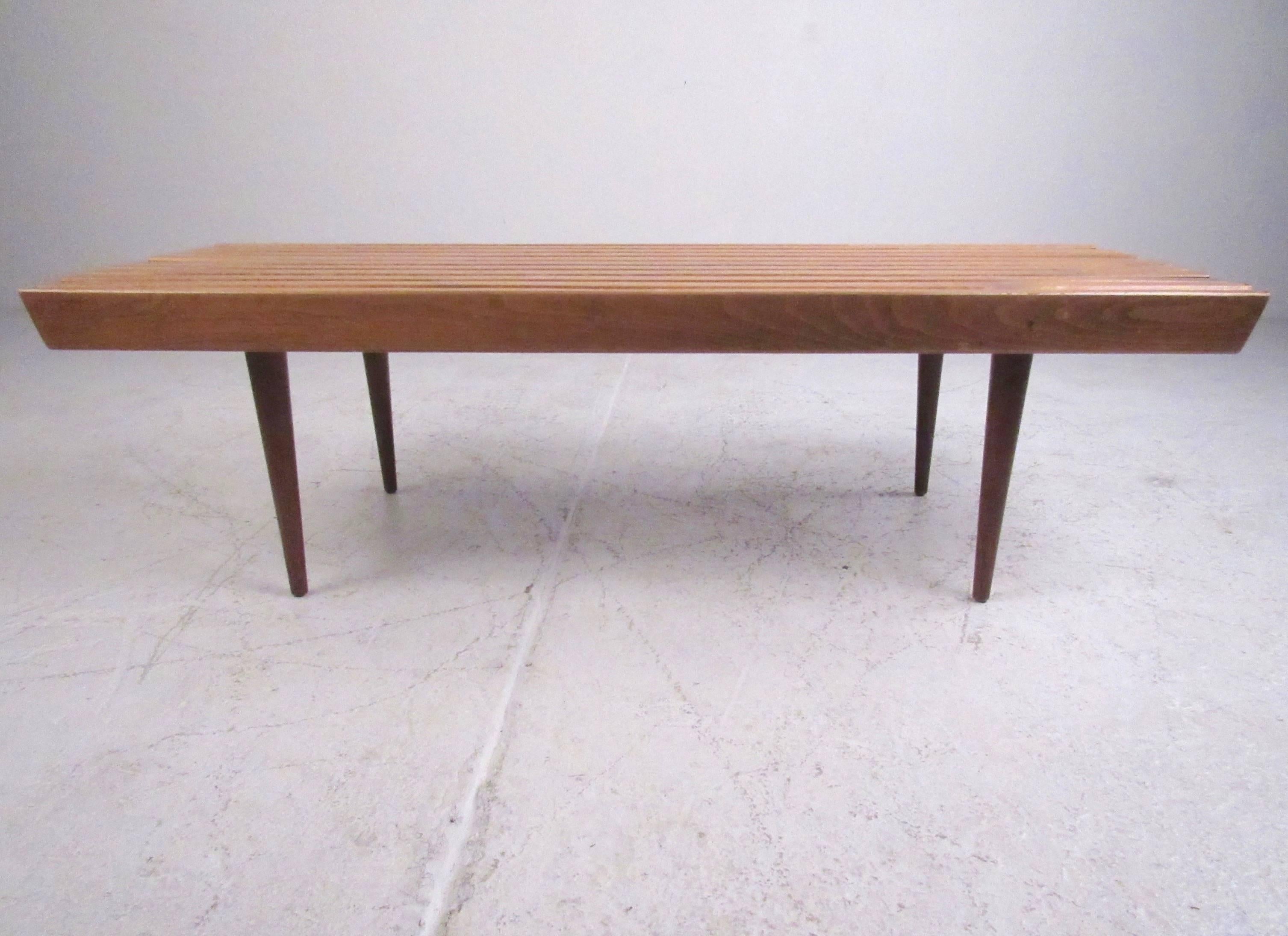 This stylish vintage coffee table features slat walnut construction and tapered hardwood legs. The sturdy Mid-Century construction makes this a perfect choice for living room coffee table or for use as a bench for occasional seating. Please confirm