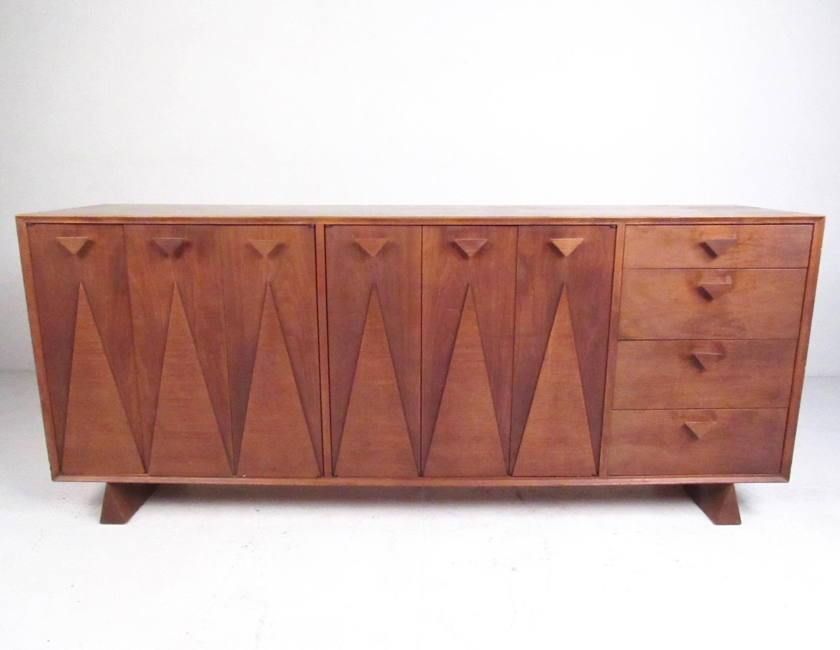 This stunning and unique bedroom set features sculpted walnut construction with unique Nakashima style design. Triangular wedge legs, drawer pulls, and carved details add to the Mid-Century Modern appeal of the matching five piece set. Sculpted