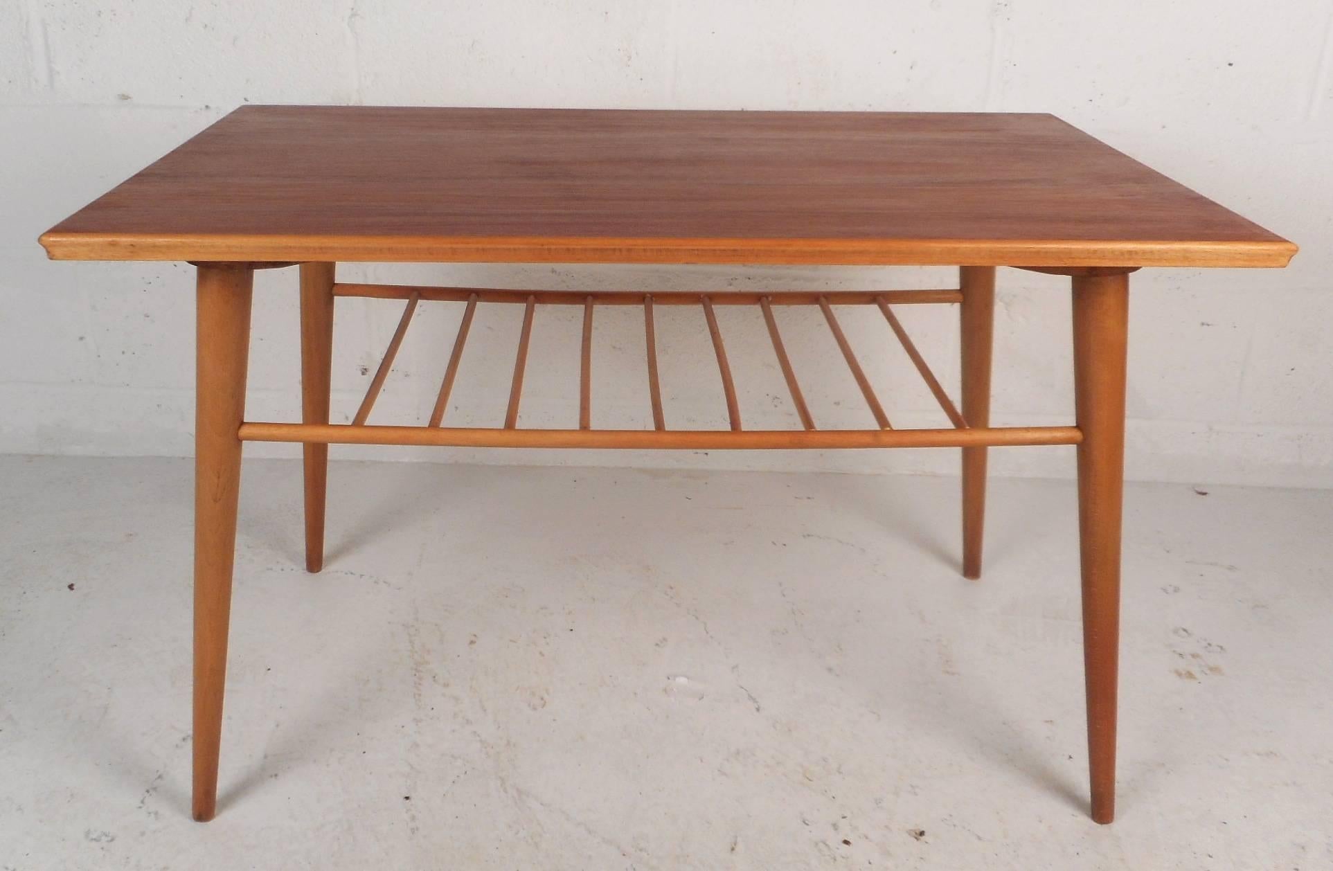 This gorgeous vintage modern end table features a unique spindle shelf underneath the top for added storage. Sleek design has gorgeous maple wood grain with long splayed and tapered legs. Elegant newly refinished Mid-Century table with unusual edges
