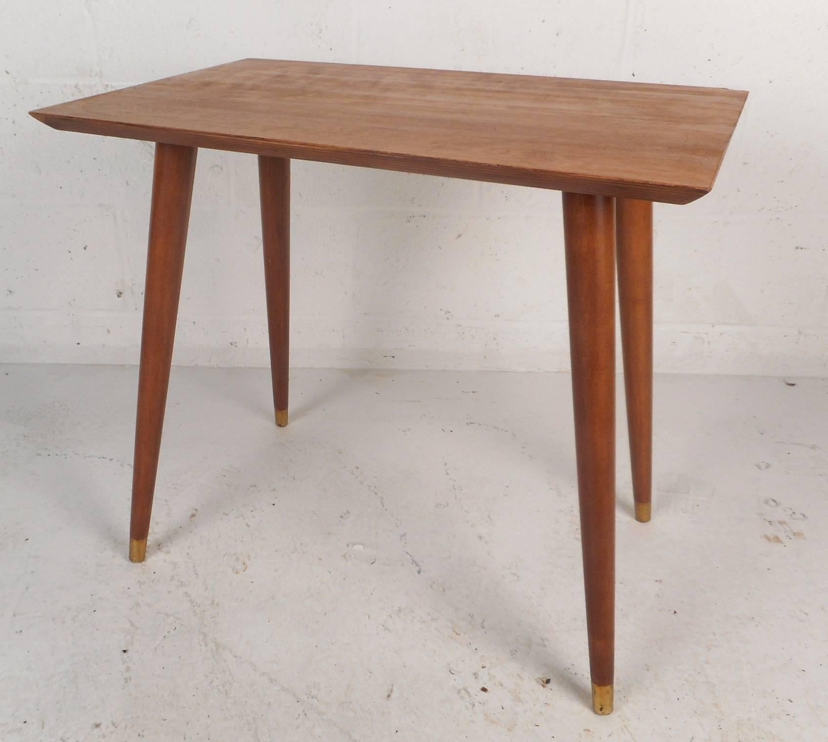 This beautiful vintage modern side table features long tapered and splayed legs with brass capped feet. Sleek design has a rectangular top with bevelled edges and gorgeous maple wood grain. This unique mid-century end table makes the perfect