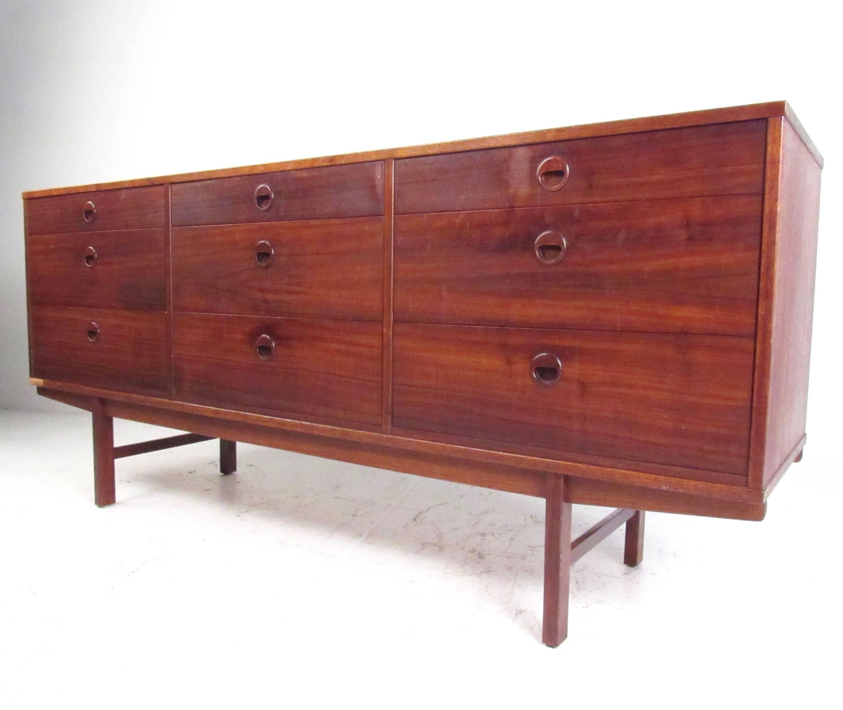 This stylish vintage teak sideboard features nine spacious drawers for storage, including felt lined top drawer for silver storage. Dated from 1960, this Mid-Century Modern piece makes the perfect storage dresser, service sideboard, or media