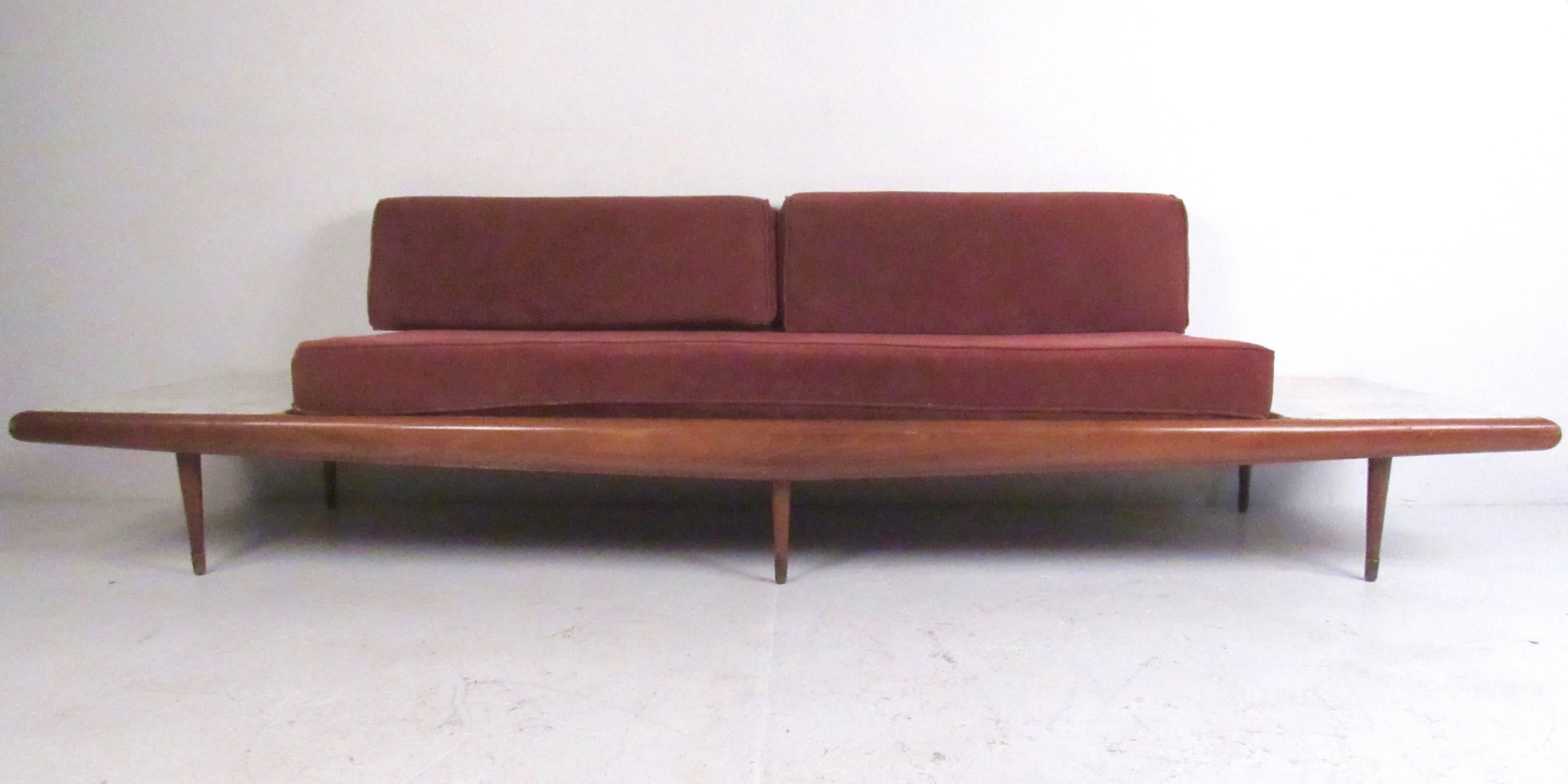 This long vintage modern sofa features sculptural walnut frame, tapered legs, and built-in marble top end tables. Designed in the Mid-Century Modern style of Adrian Pearsall, this comfortable daybed features upholstered seating and makes an