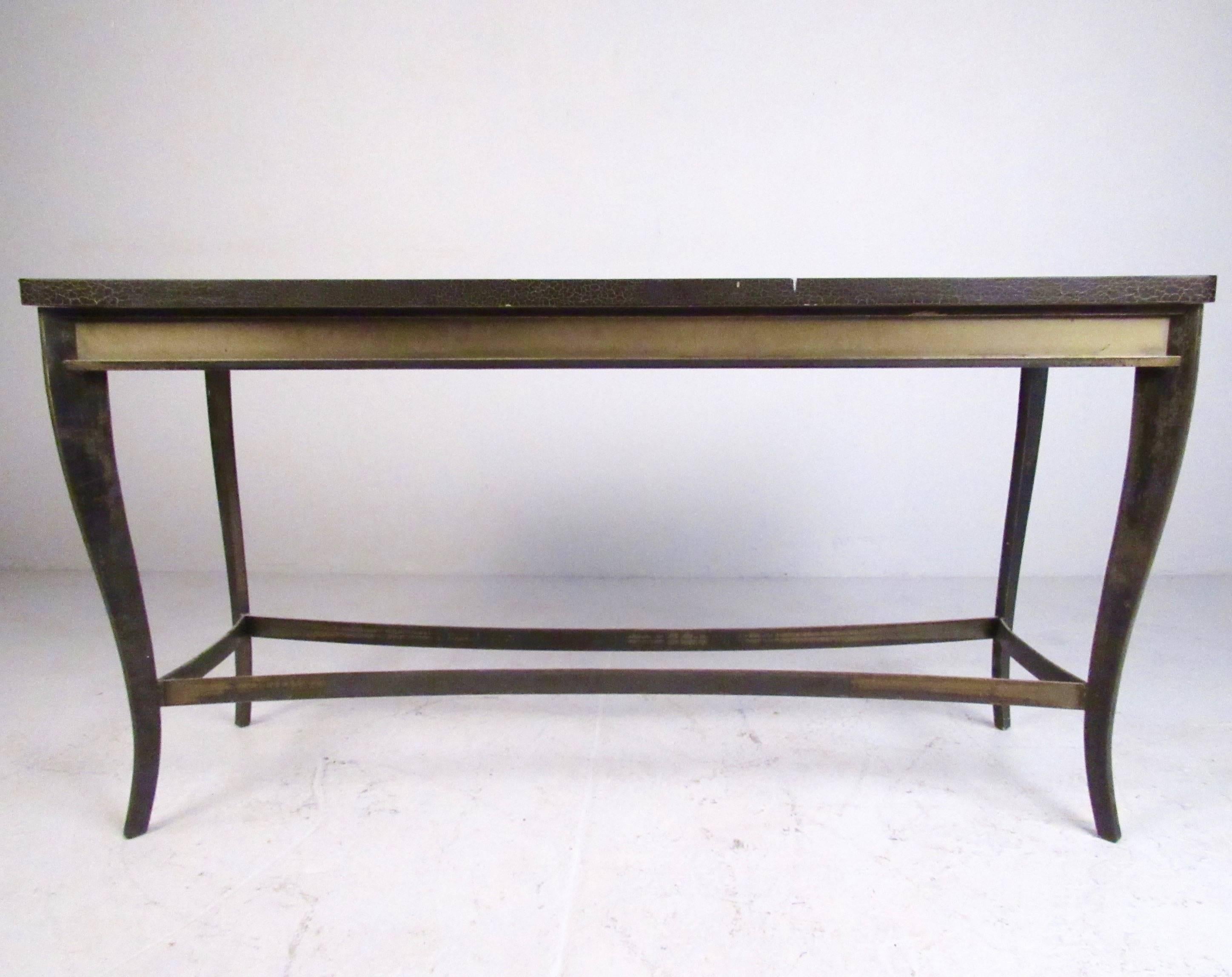 This substantial vintage console table features a heavy metal base and faux finish top. The metal has a unique patina finish, and the piece makes a stylish addition to any interior, from entryway display table, living room sofa table, or as a unique