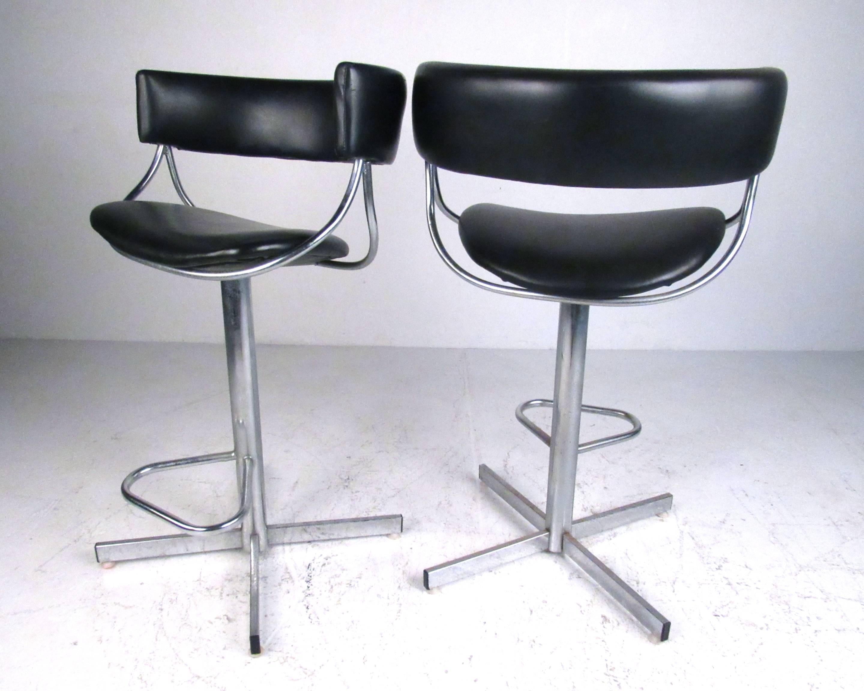 This set of four chrome swivel barstools feature unique Mid-Century design with stylish barrel seats. Metal footrests and sleek vintage modern style add to the comfort of this matching set of four American made stools by Jansko. Ideal for home or