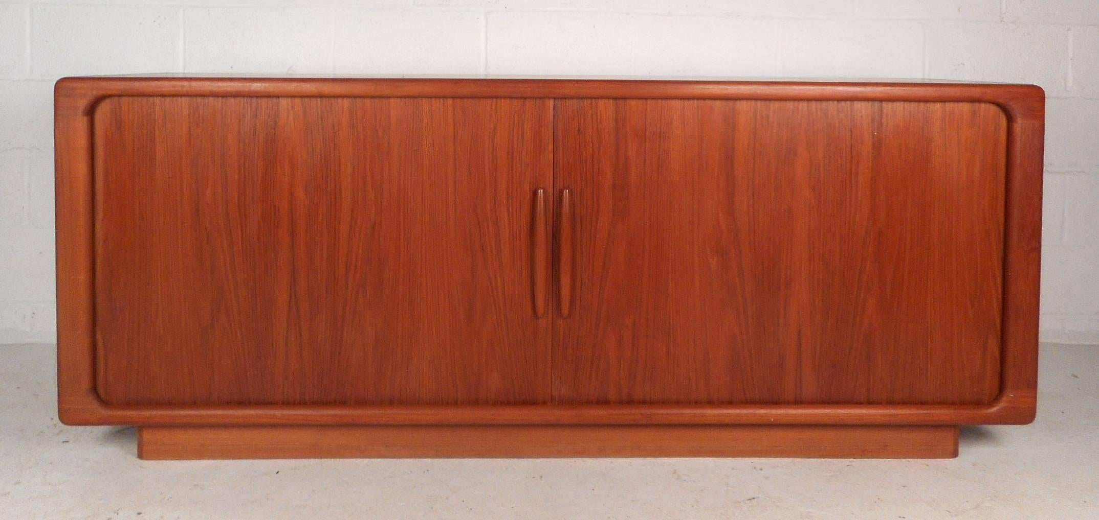 Elegant Mid-Century Modern sideboard with two tambour doors that open smoothly and hide two shelving compartments and five small drawers. Stunning vintage teak wood grain, dove tail joints, and unique door pulls add to the allure. This impressive