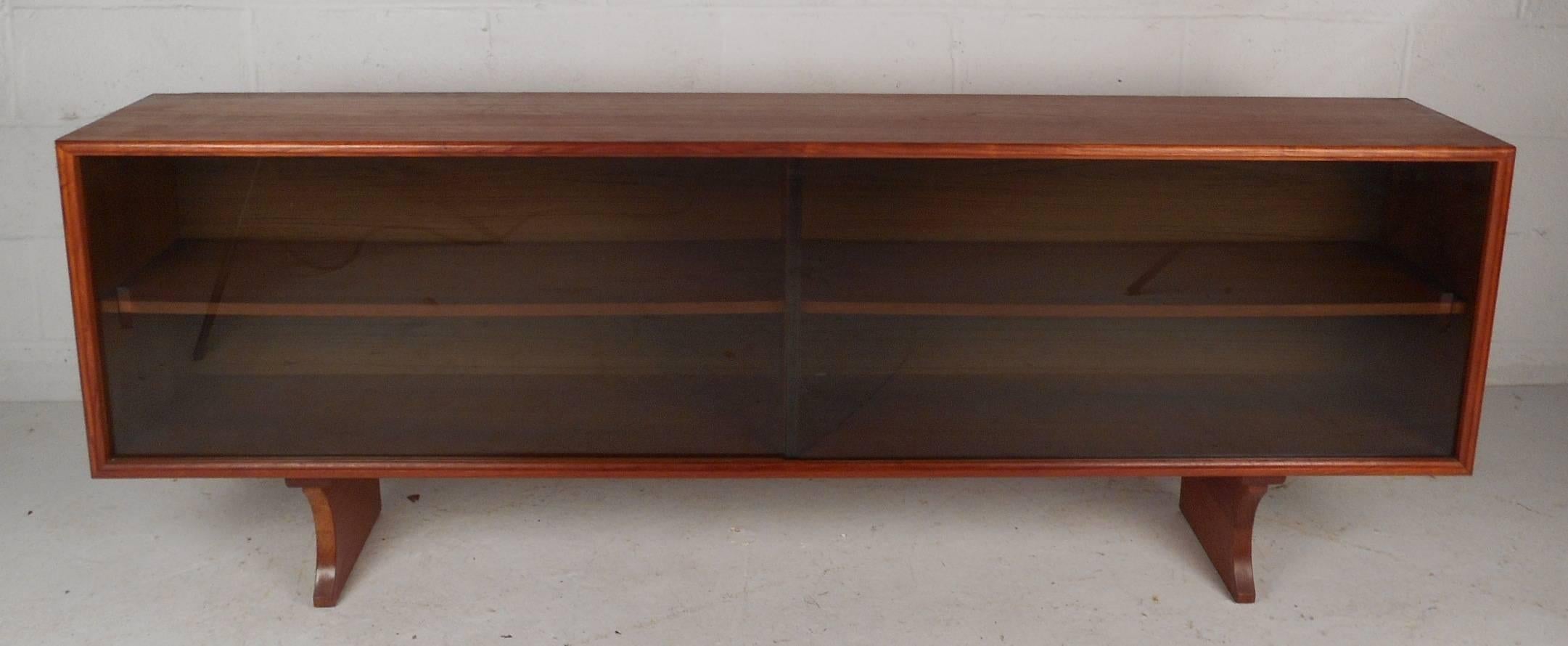 Stunning vintage modern long cabinet with smoked glass sliding doors makes the perfect addition to any modern interior. This versatile Mid-Century piece can be placed on top of a sideboard or set on the floor. This lovely case piece has two large