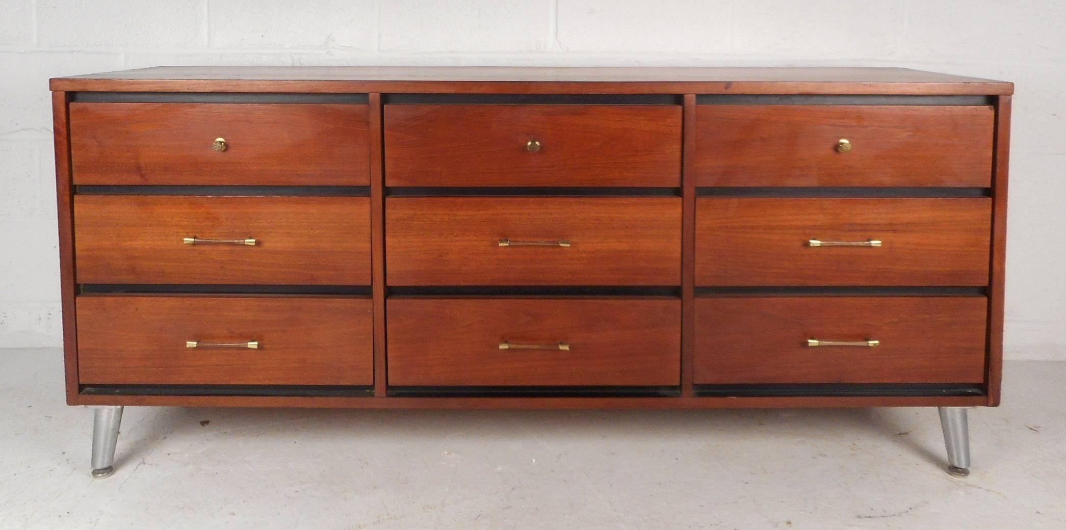 This beautiful vintage modern dresser features nine hefty drawers with a unique variety of pulls. This one of a kind dresser has unusual splayed and tapered metal legs. Stunning Mid-Century case piece displays an ebony finish in between each drawer.