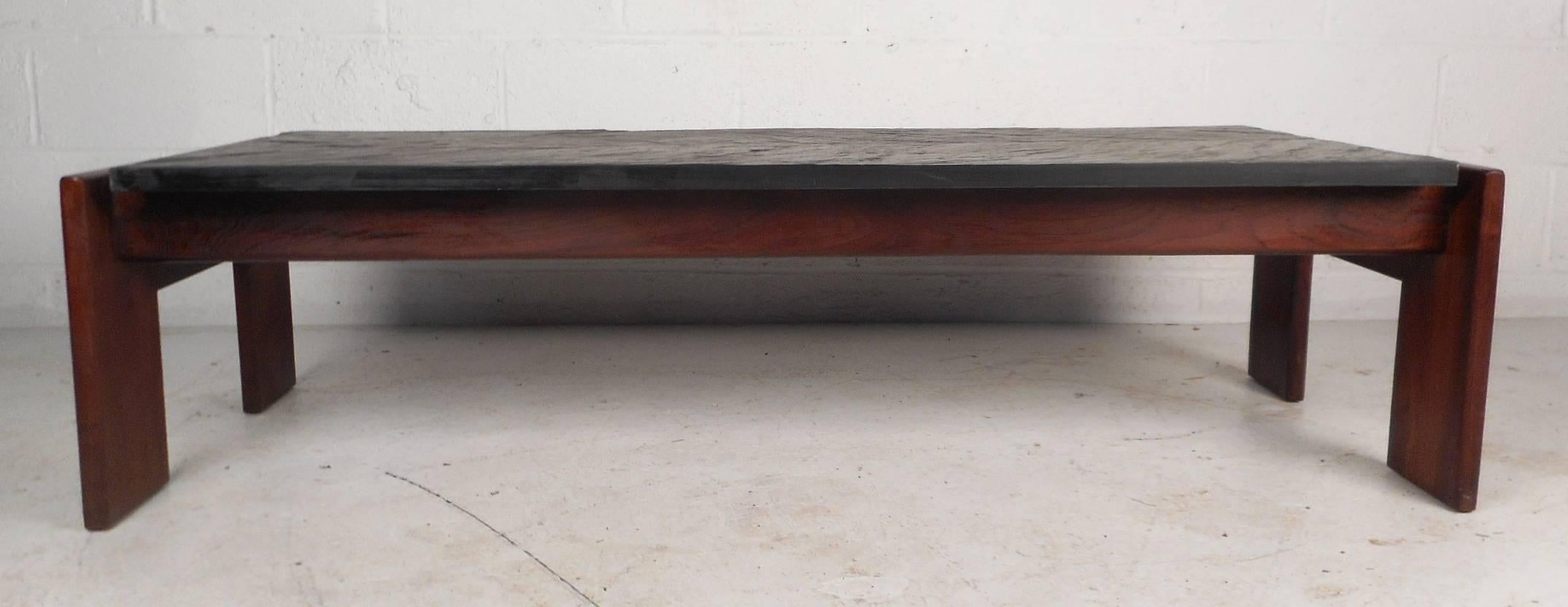 This stunning vintage modern coffee table features a unique floating top design with a solid walnut frame. This beautiful Mid-Century piece has a heavy black slate tabletop with excellent texture. Simple and straight lined design shows true