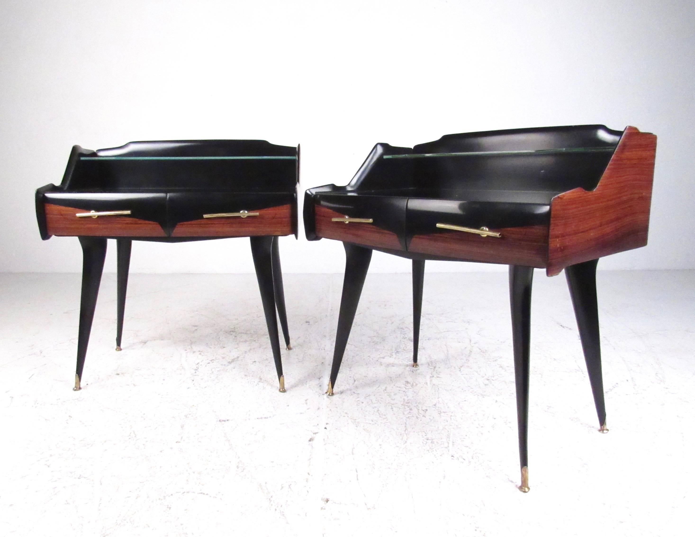 Cette paire de tables de nuit des années 1950 présente un design moderne italien élégant et constitue une excellente table de chevet à deux niveaux pour tout intérieur. Une élégante tablette en verre, un cadre sculpté de deux tons et des pieds