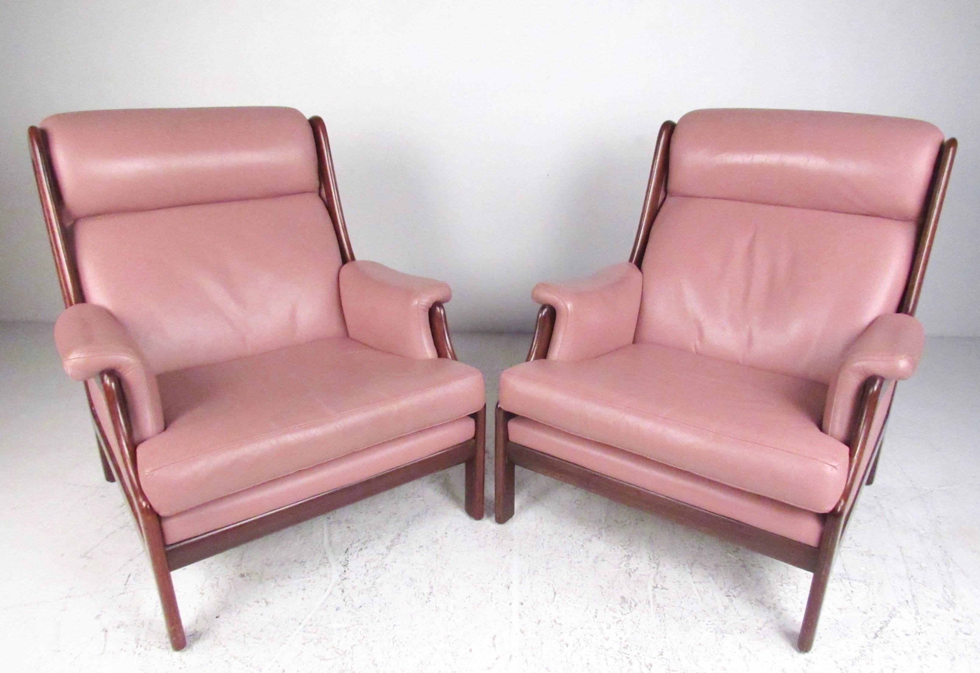 This stylish pair of Scandinavian Modern lounge chairs boast leather high back seats, sturdy sculptural teak frames and timeless modern comfort. Well padded seats and armrests make these a comfortable Mid-Century lounge chair for any interior.