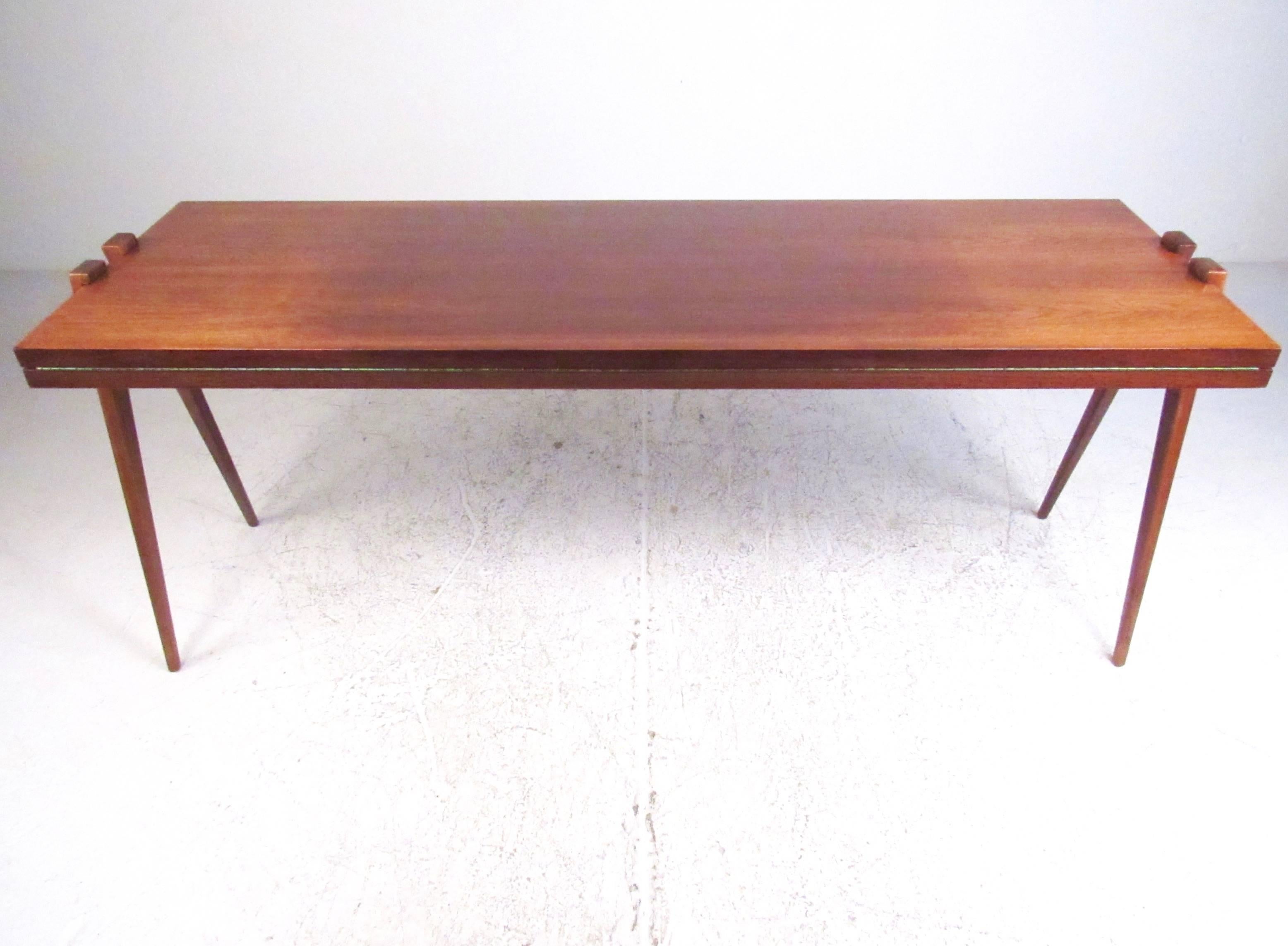This sleek and stylish Mid-Century dining table features the innovative design of American Phillip Enfield. Tapered legs shift position to open the tabletop from 24 inches x 72 inches to 40 inches x 72 inches. The unique design of this versatile
