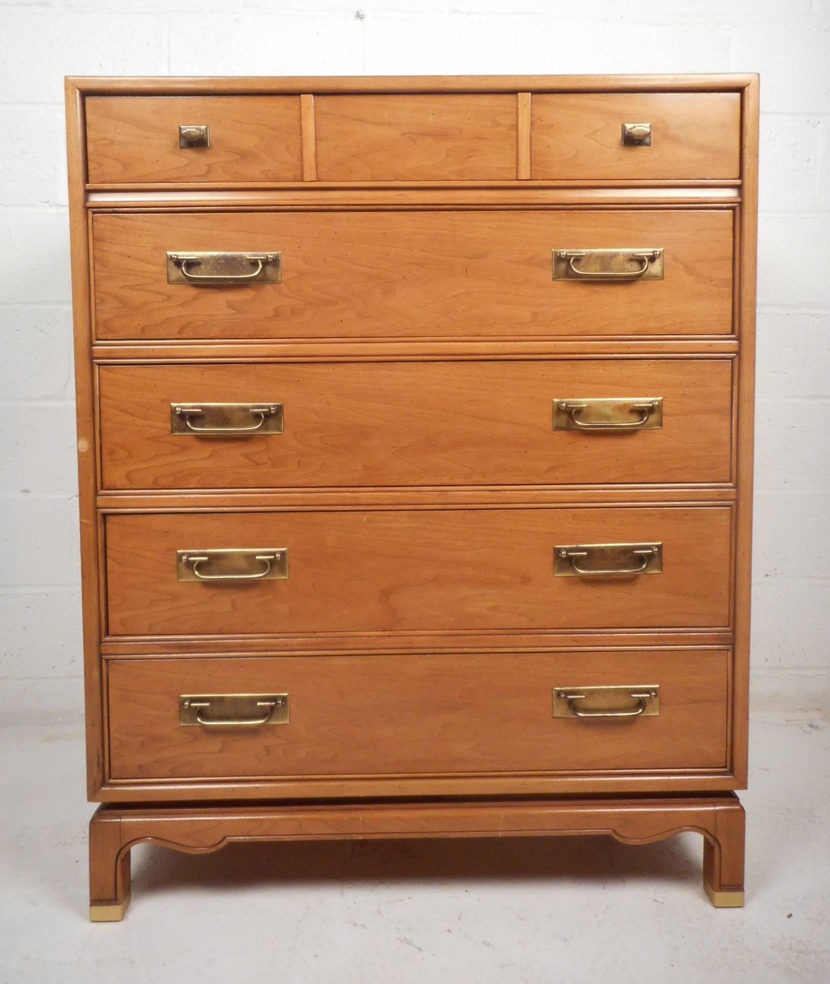 This elegant vintage modern gentleman's chest features five hefty drawers with various brass pulls ensuring plenty of room for storage. Elegant light walnut wood grain and a unique sculpted base adds to the Mid-Century appeal. Sturdy and sleek