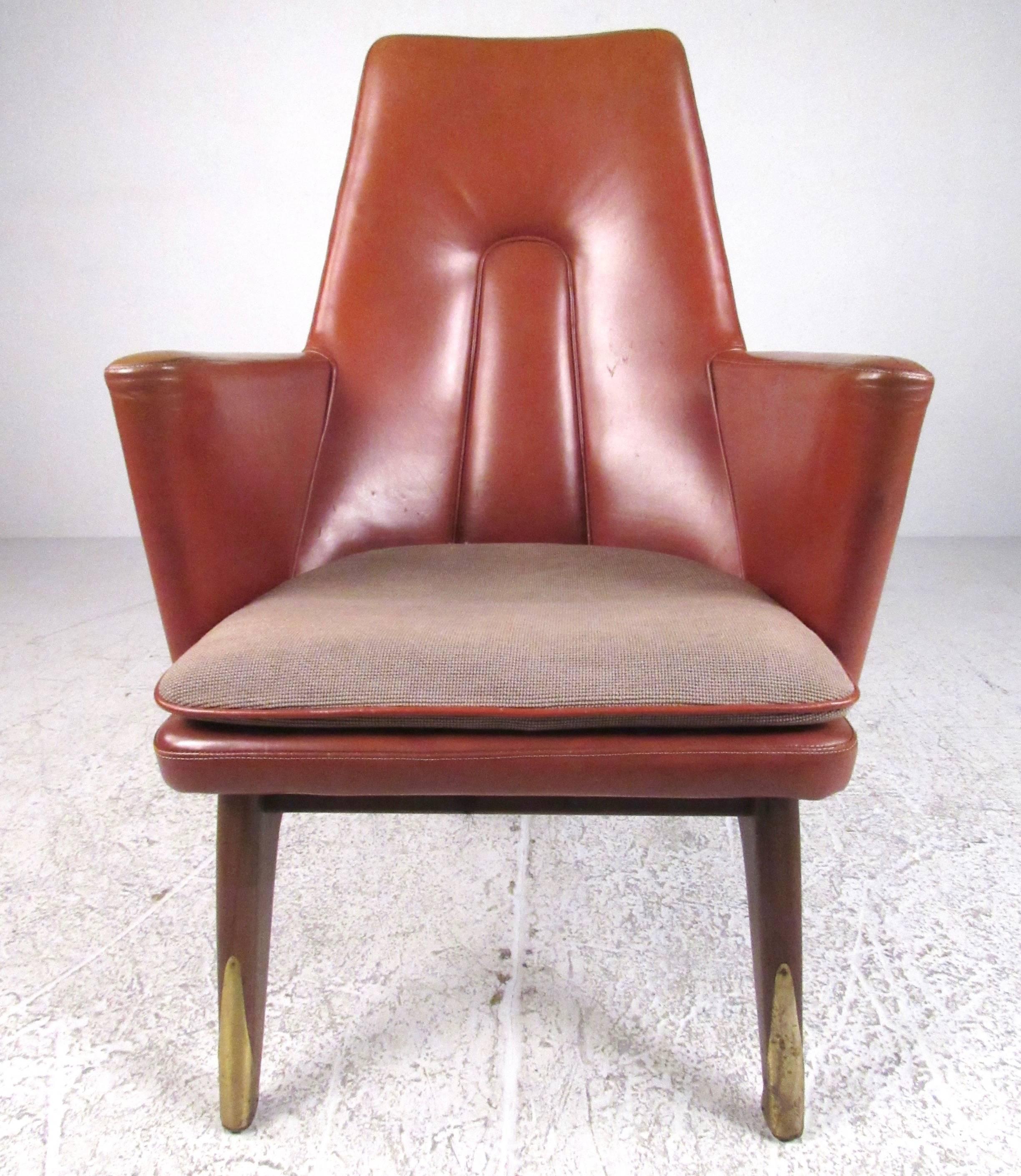 This unique leather and walnut lounge chair features a sculpted high back seat with tapered walnut legs. Stylish brass sabots and stitched details add to the Mid-Century Modern charm of this comfortable side chair, perfect for office or home. Please