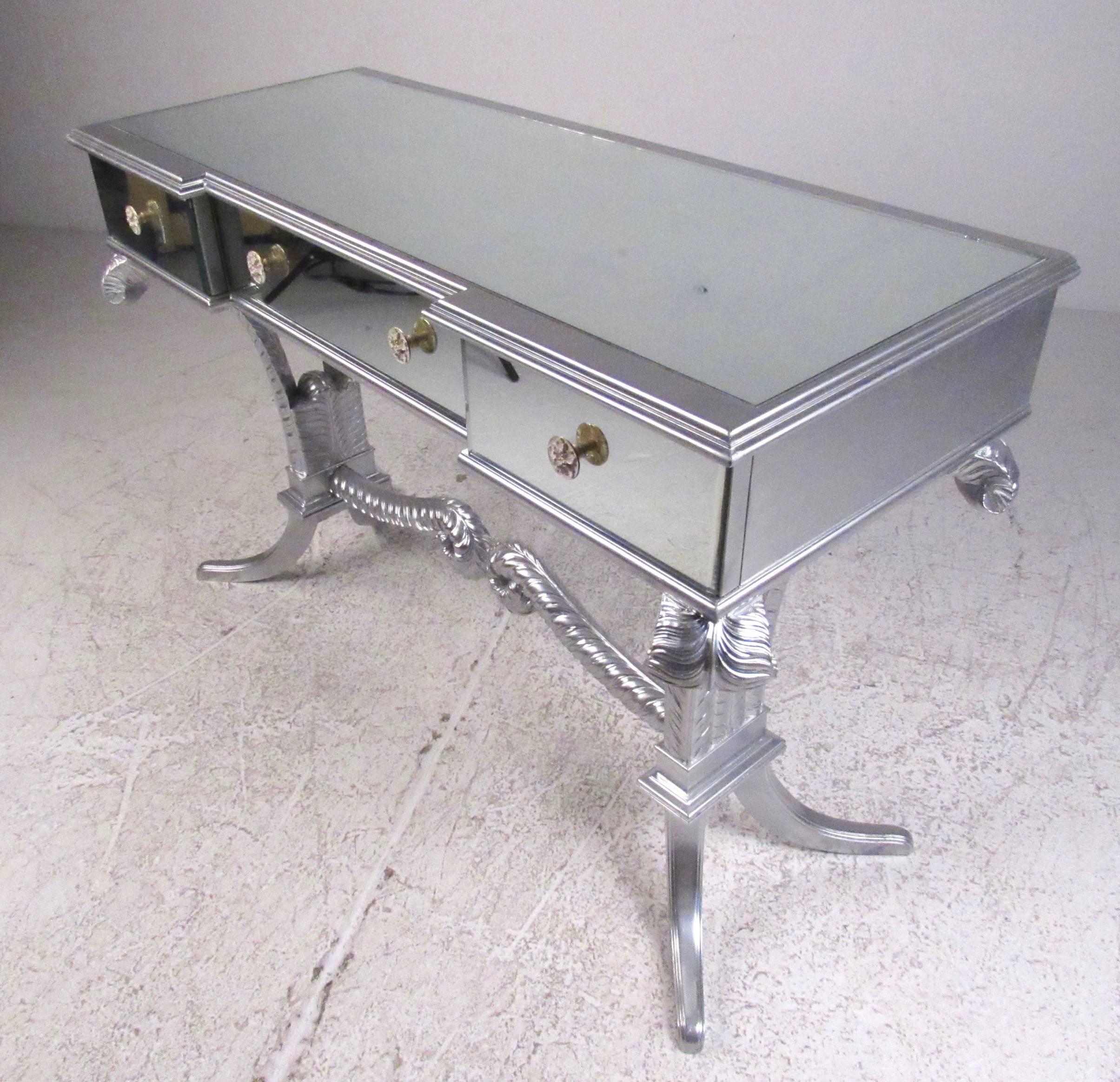 This unique three-drawer mirrored table features ornately designed base with matching drawer pulls. Stylish decorator table is perfect for use as a vanity or hall table. Please confirm item location (NY or NJ).