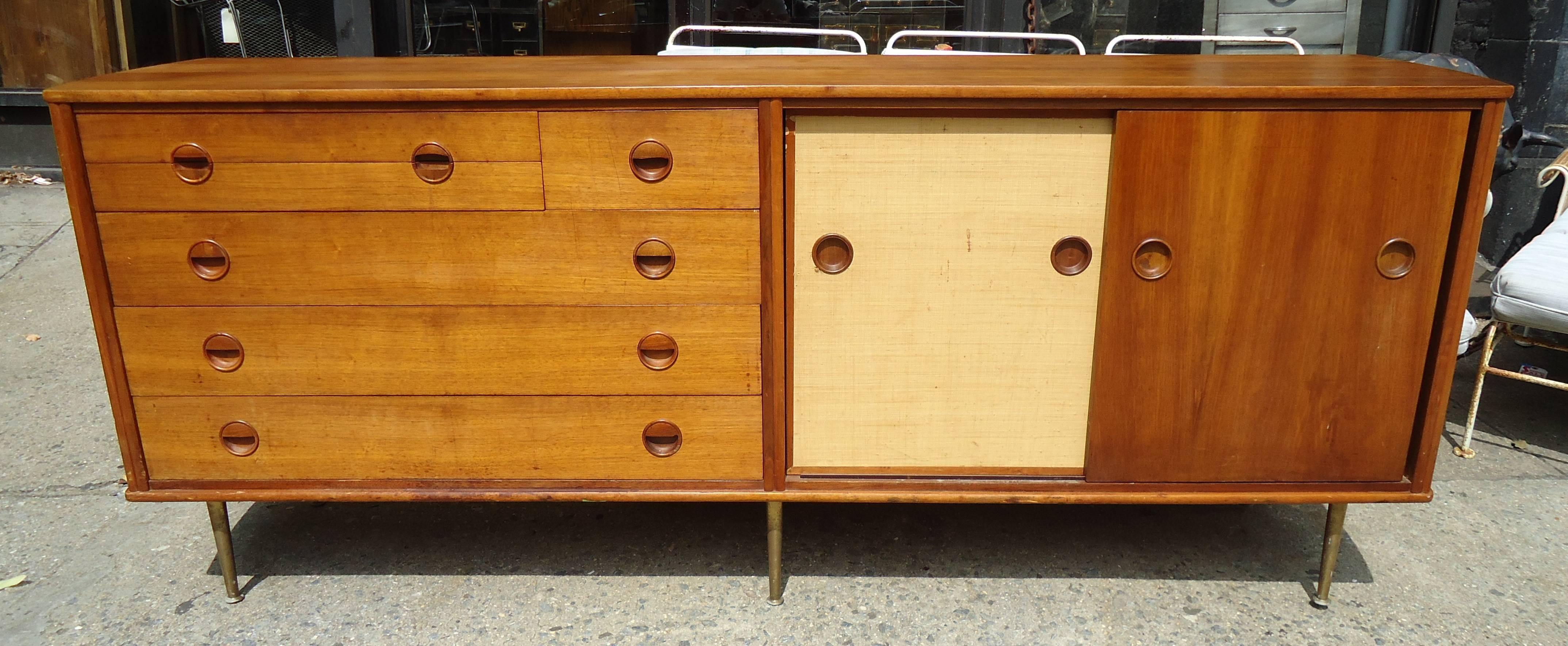 Mid-Century Danish server with teak grain and raffia (palm plant) doors set on beautifully tapered brass legs. Curved sides and sculpted handles.

(Please confirm item location - NY or NJ - with dealer).
 