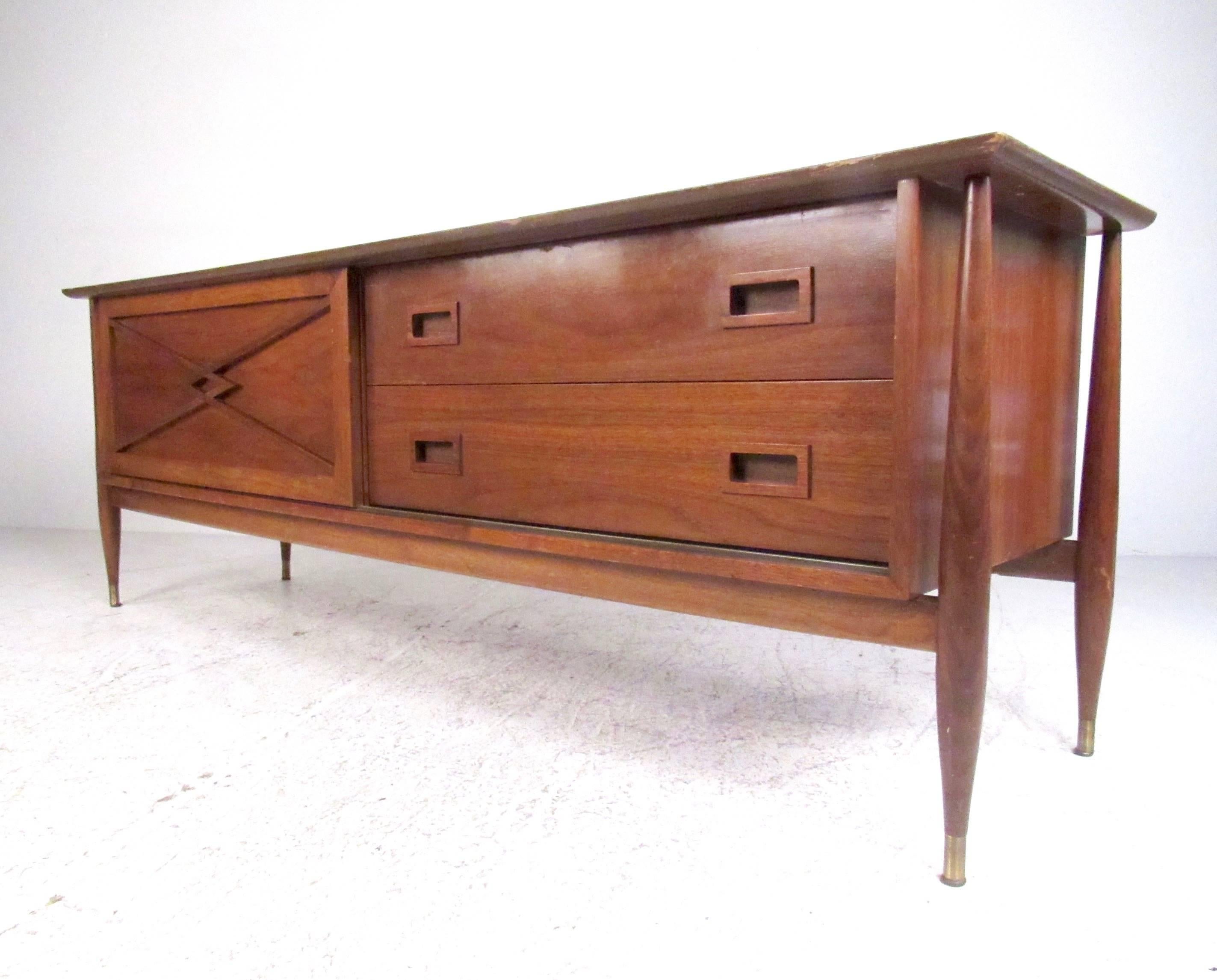This stylish low credenza makes a perfect media storage console, with sliding cabinet storage and spacious drawers. The low height makes this ideal for use as a television console in living room or office. Mid-Century Modern walnut finish includes