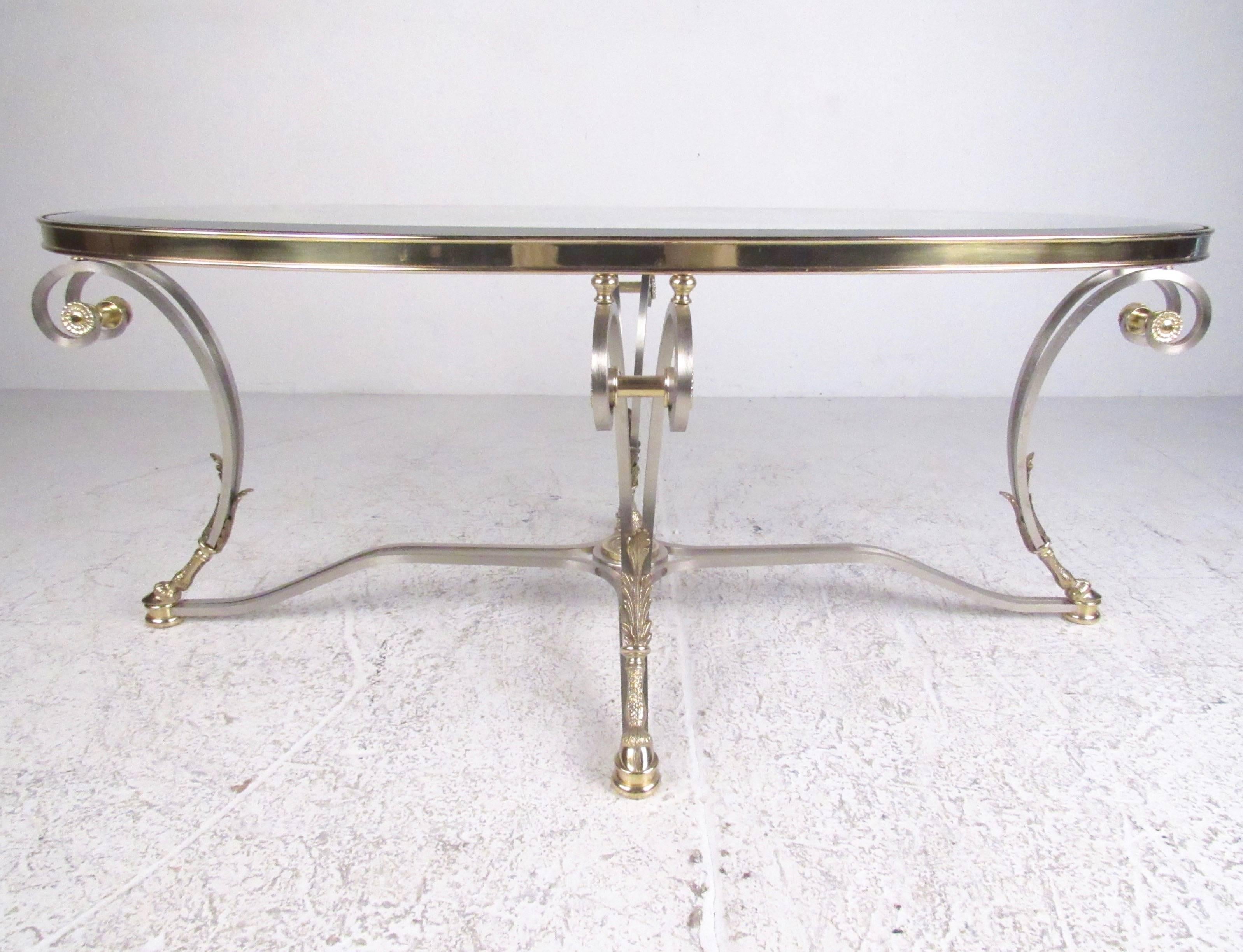 This stylish vintage modern coffee table features brushed steel finish with ornate brass details. This Regency style oval coffee table is the perfect for home or business seating area, please confirm item location (NY or NJ).