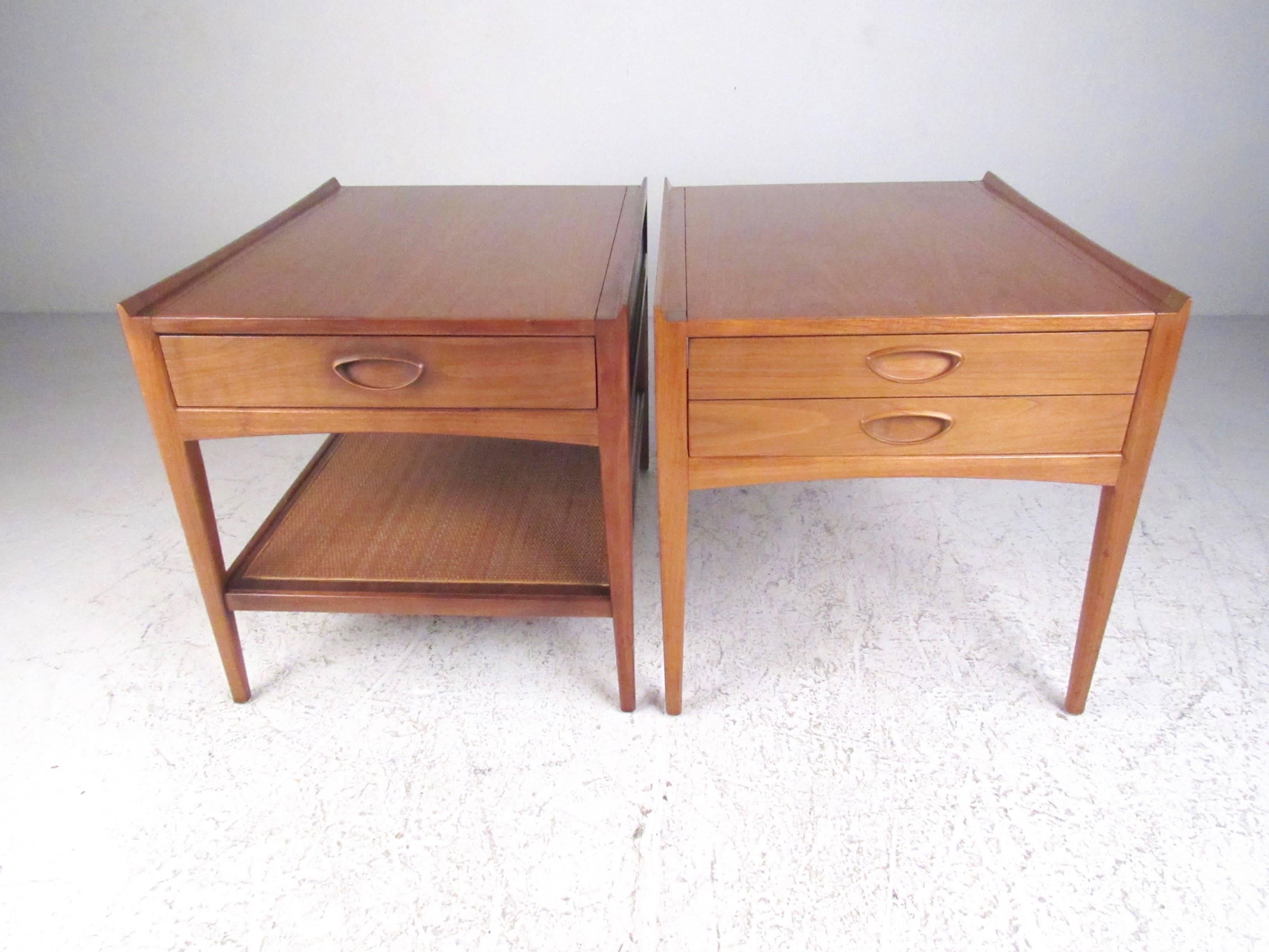 This stylish pair of vintage walnut end tables feature raised edge tops, cane storage shelf, and spacious drawer for storage. Perfect tables for bedside nightstands or living room end tables. Unique Mid-Century style includes rich natural wood