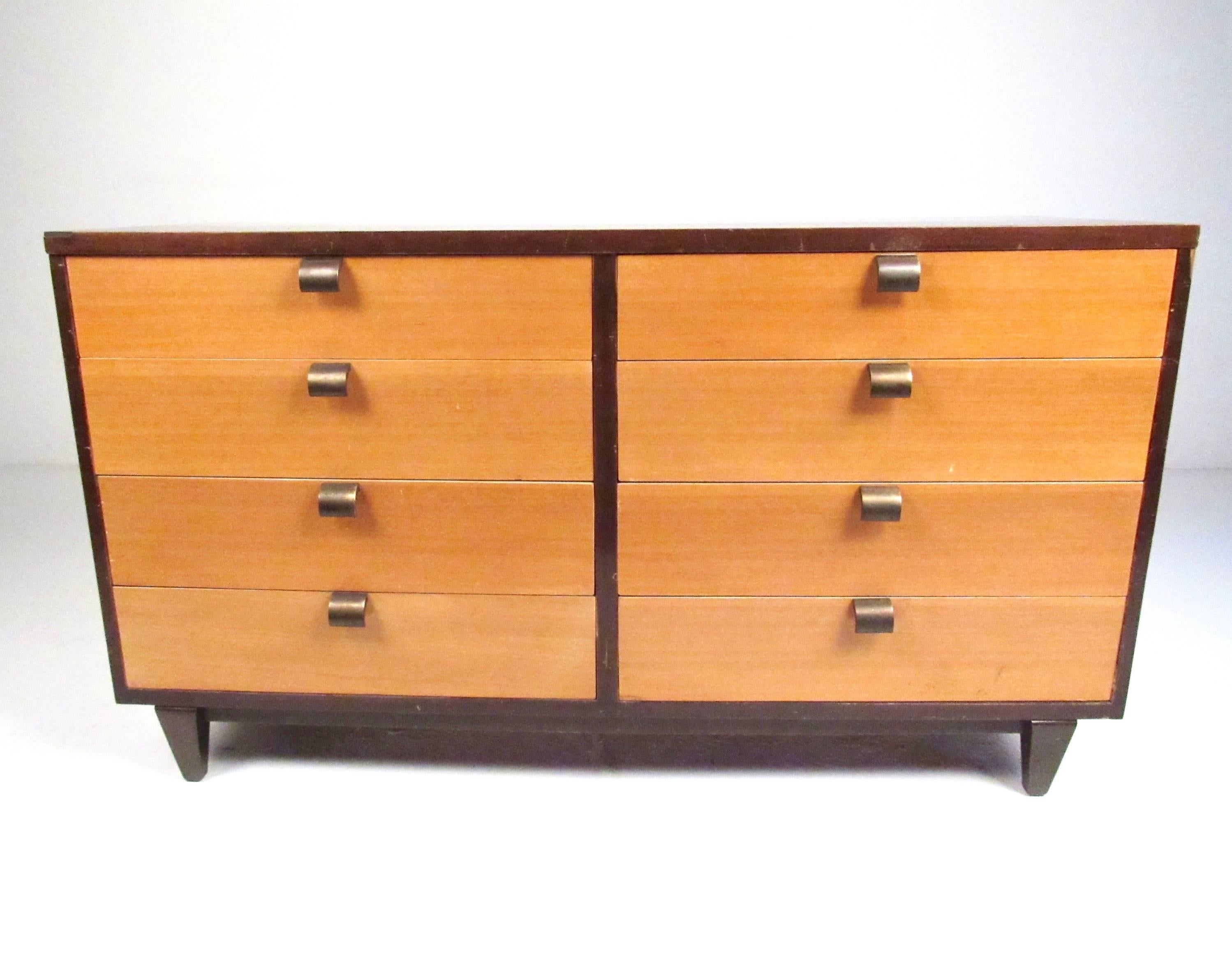 This unique pair of Mid-Century Modern bedroom dressers include a low six drawer dresser with a matching highboy. Unique two-tone wood finish is complemented wonderfully with tapered legs and stylish brass handles. Dividers split up the pairs