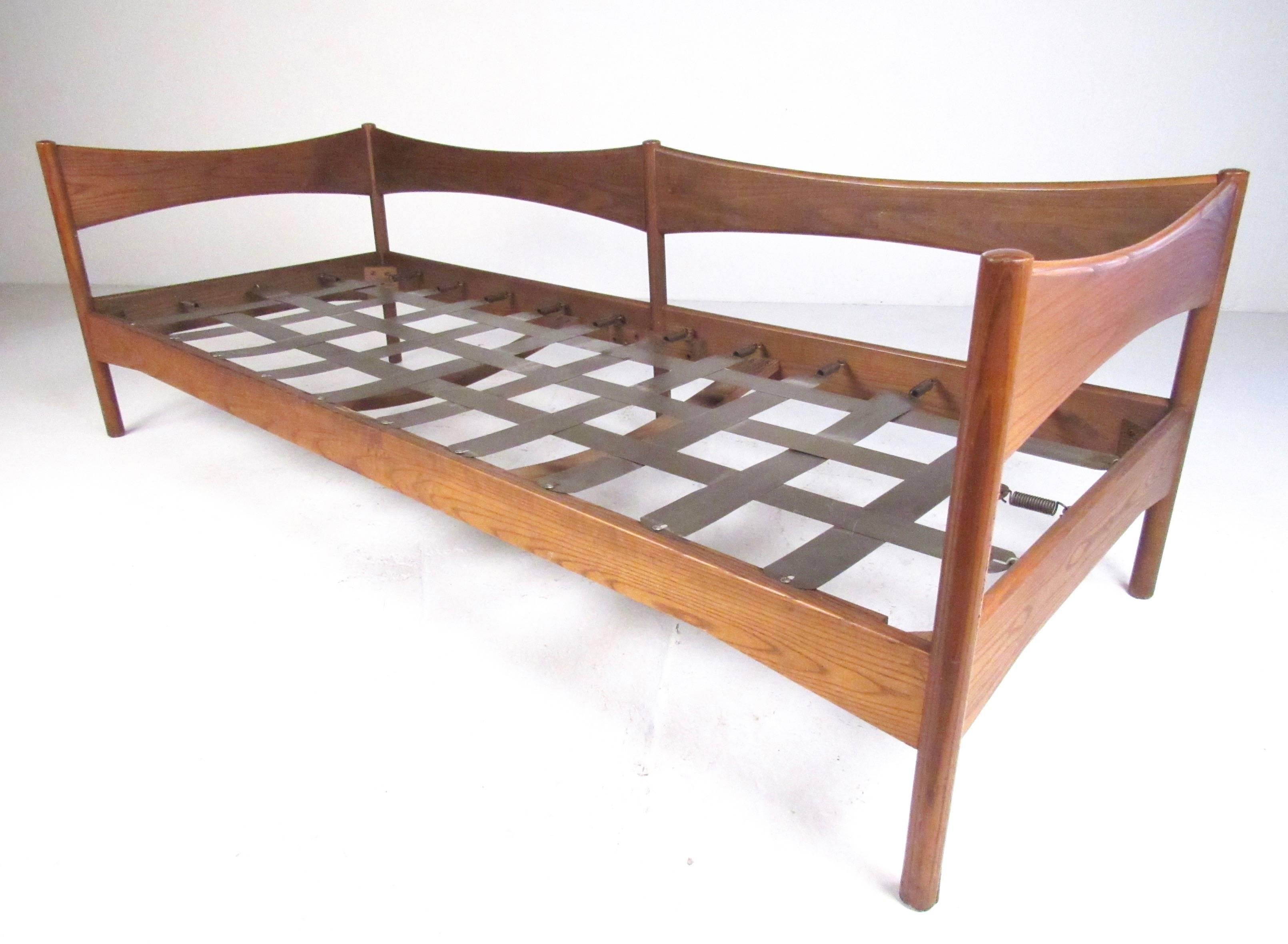 This uniquely shaped Mid-Century Modern daybed features sturdy oak and metal construction, with unique sculptural details. Wide woven metal seating area allows for a spacious upholstered cushion and can be used as a daybed or upholstered with back