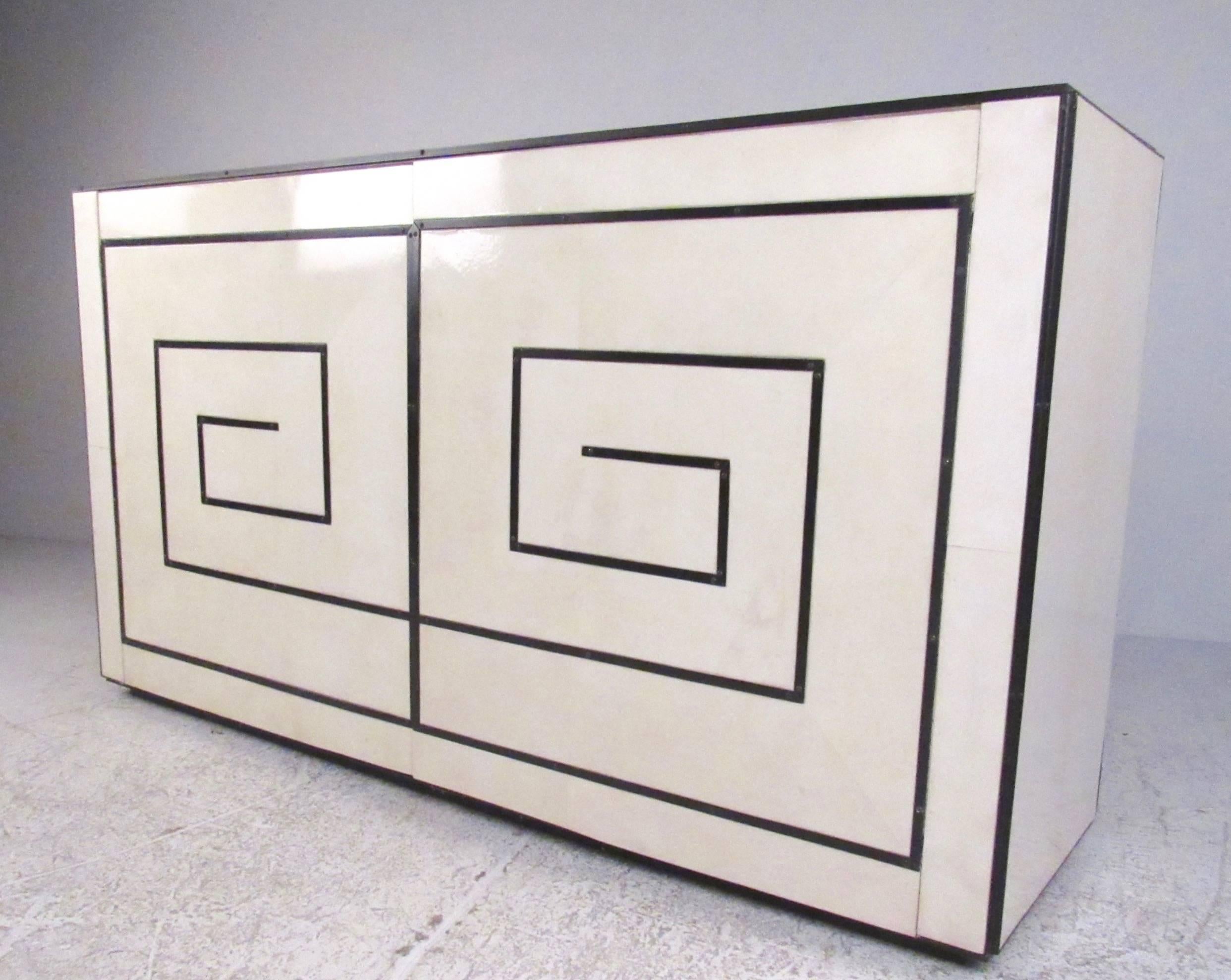 This unique modern credenza features a stylish parchment finish with unique black trim. Spacious interior cabinet space offers plenty of storage space with shelves and drawers perfect for dining room or office storage. Exquisite cabinet by Garrison