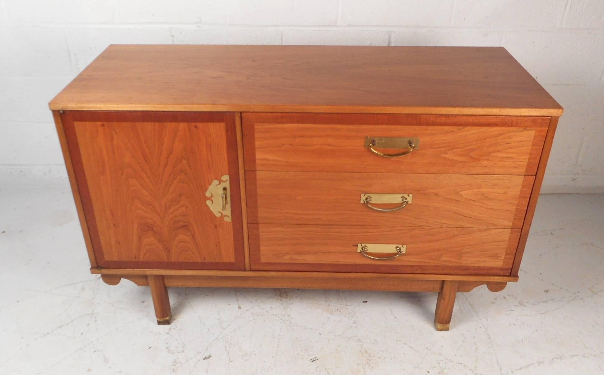 This beautiful vintage modern buffet has plenty of room for storage within its three drawers and hidden compartment with a shelf. Sleek design with brass pulls on each drawer and cabinet. This unique case piece has brass handles on each side