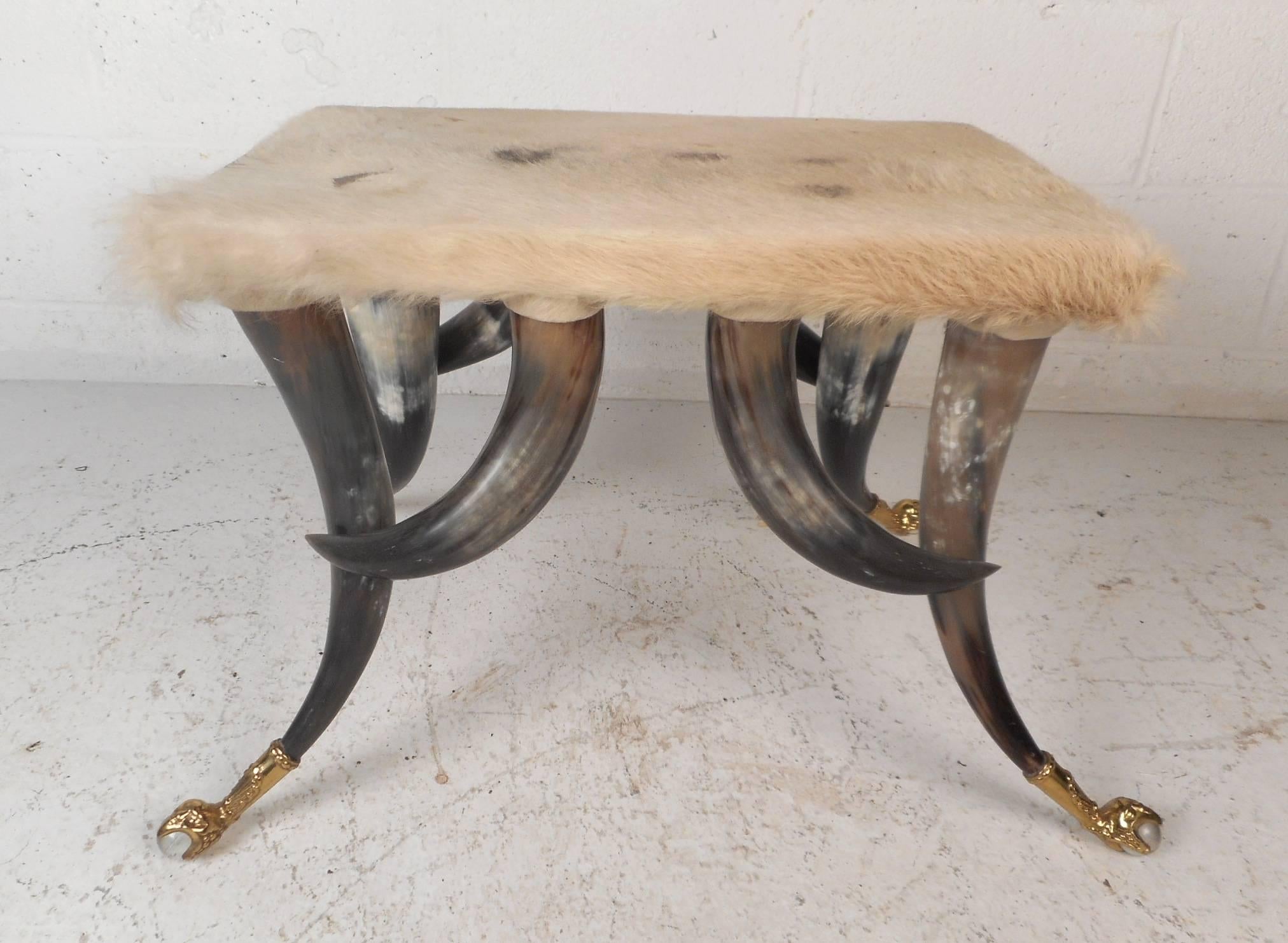 This beautiful Mid-Century Modern ottoman features a soft cowhide top with a unique horn base for legs. Sleek design with brass claw feet holding a clear ball. Exquisite detail and sturdy construction makes this vintage modern stool the perfect