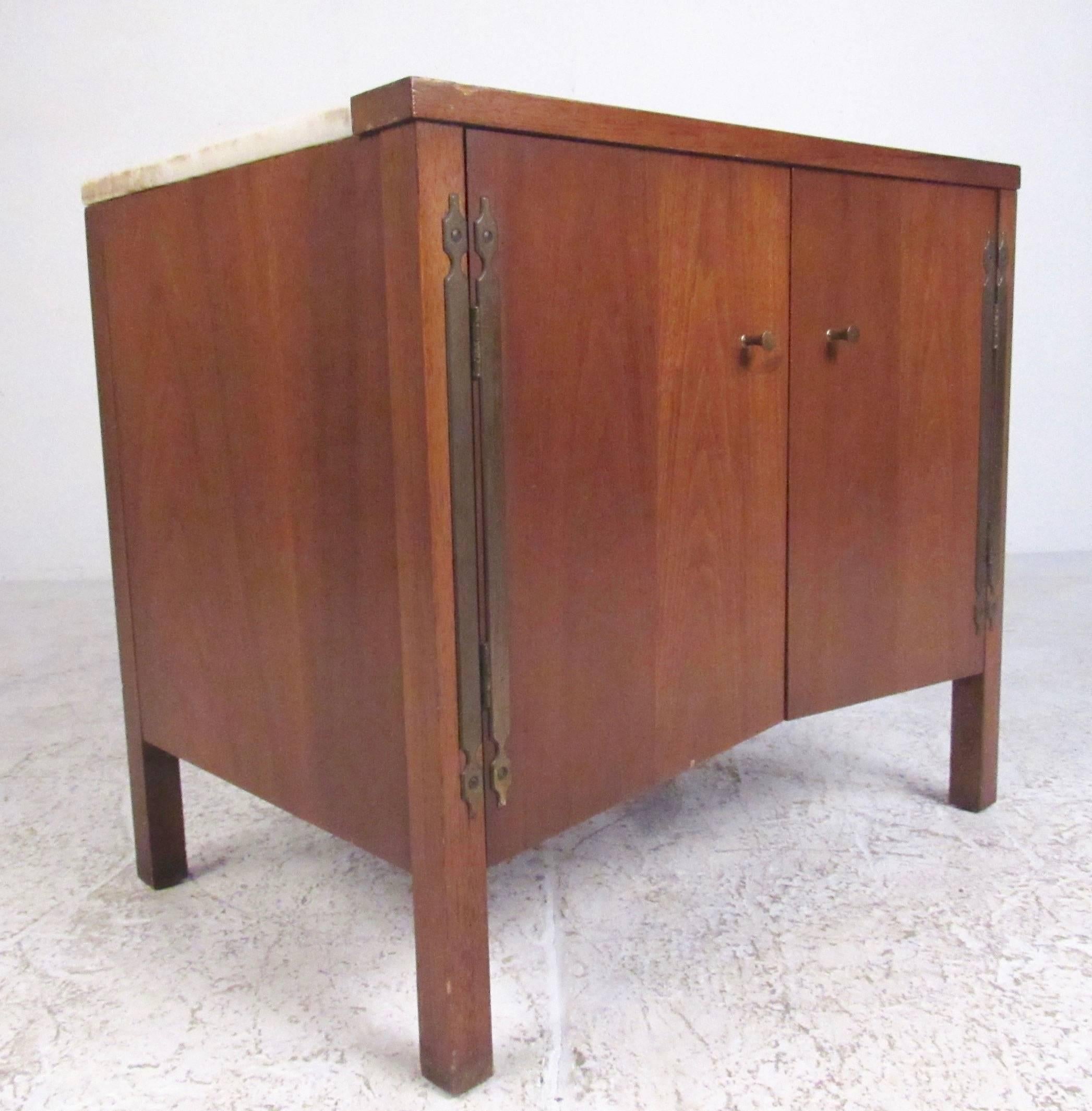 This stylish midcentury end table features quality Drexel construction with spacious shelved cabinet storage. Vintage marble-top creates a beautiful contrast with the vintage walnut finish and brass trim hinges. Perfect storage table for bedside or