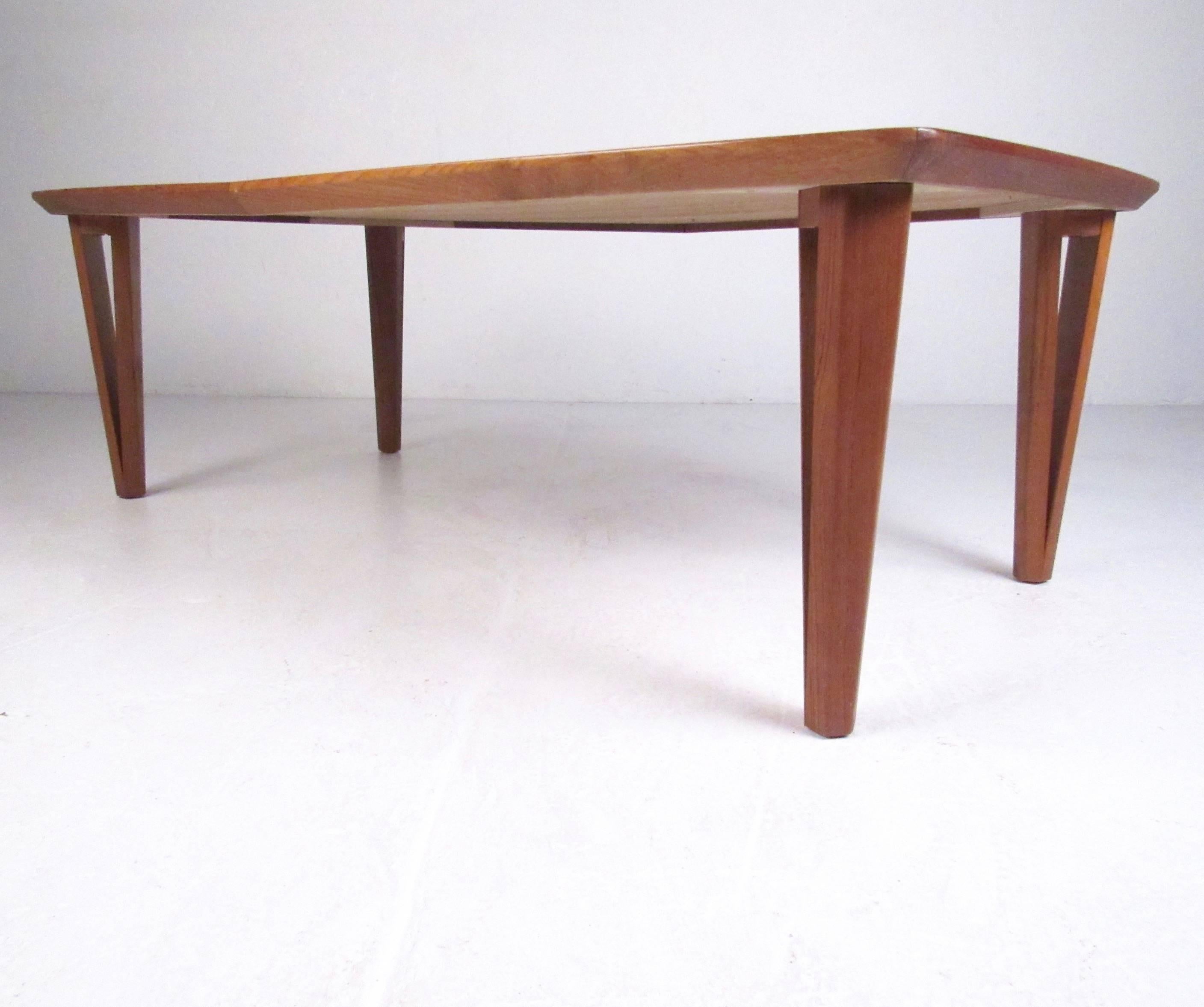 This unique Mid-Century Modern coffee table features stylish and sturdy Danish teak construction and is perfect for home or office. Vintage style showcased with sculpted triangular legs that offer a hairpin feel and add to the impressive