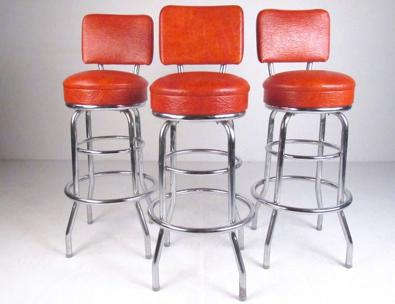This stylish retro set of vintage modern bar stools feature vinyl swivel seats, sturdy metal frames, and circular metal footrest. Perfect set of bar height stools for home or business bar seating. Please confirm item location (NY or NJ).