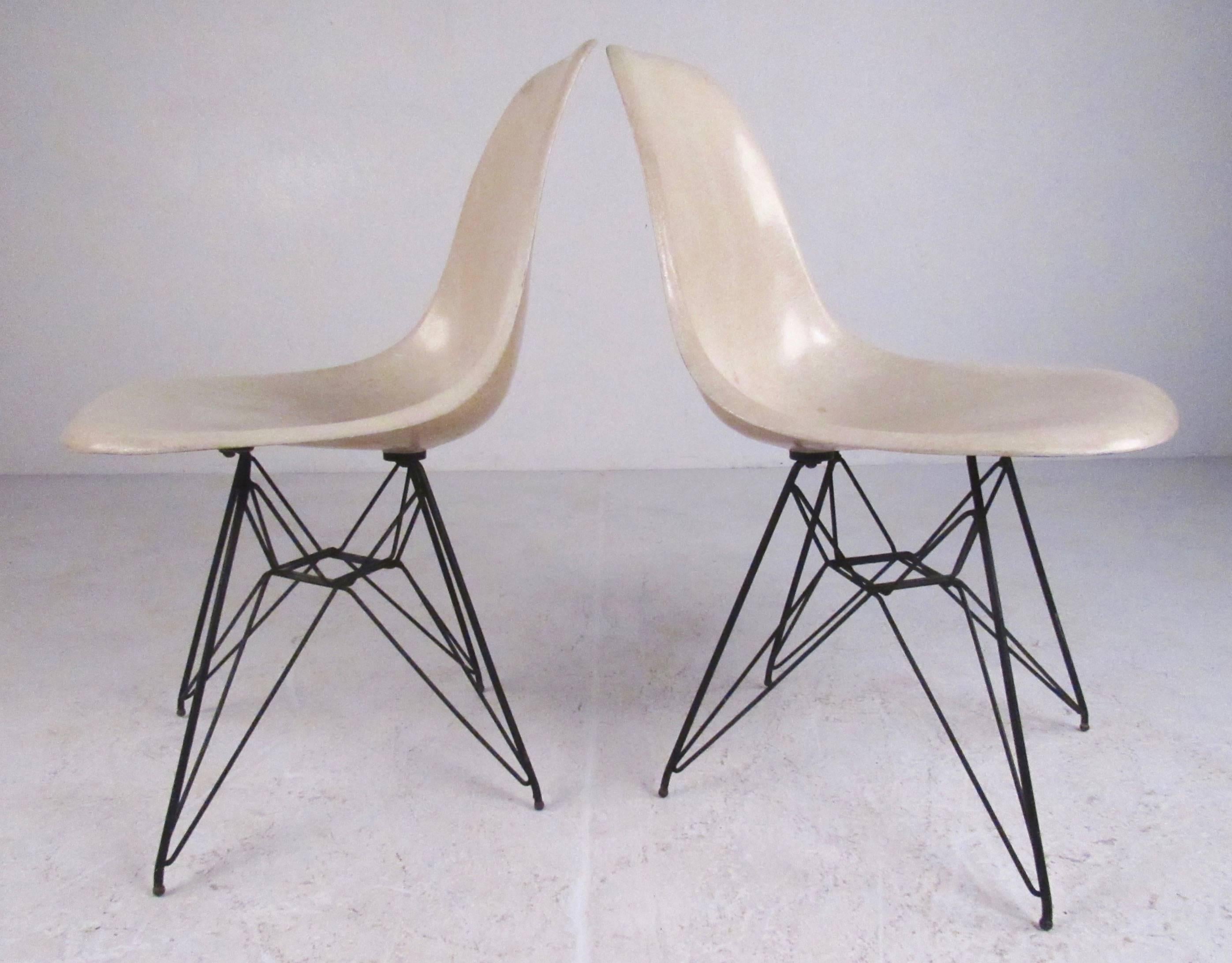 Dieses ikonische Paar moderner Beistellstühle aus der Jahrhundertmitte zeichnet sich durch das klassische Charles-Eames-Eiffelturm-Untergestell und geformte Glasfasersitze aus. Der stilvolle, moderne Vintage-Komfort macht dieses Paar zur perfekten